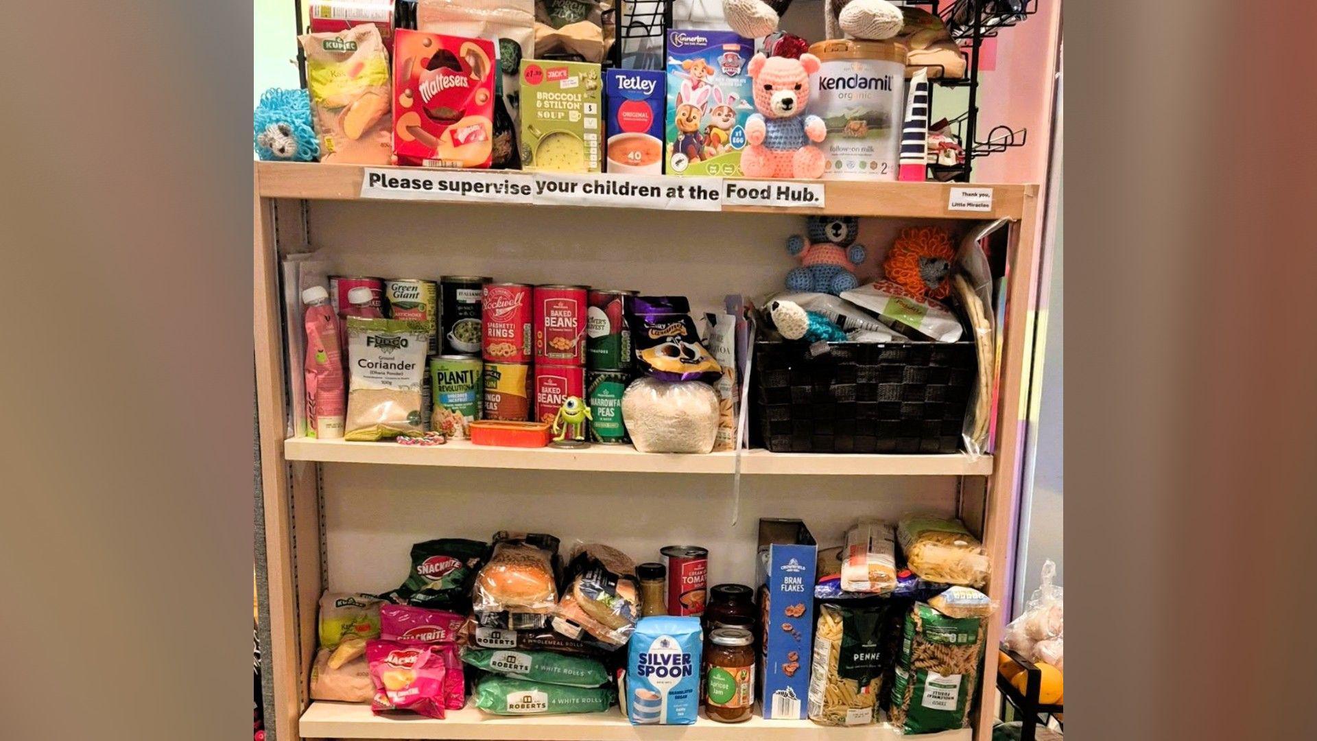 Shelves of food items including boxes of soup, tins and jars placed next to each other.