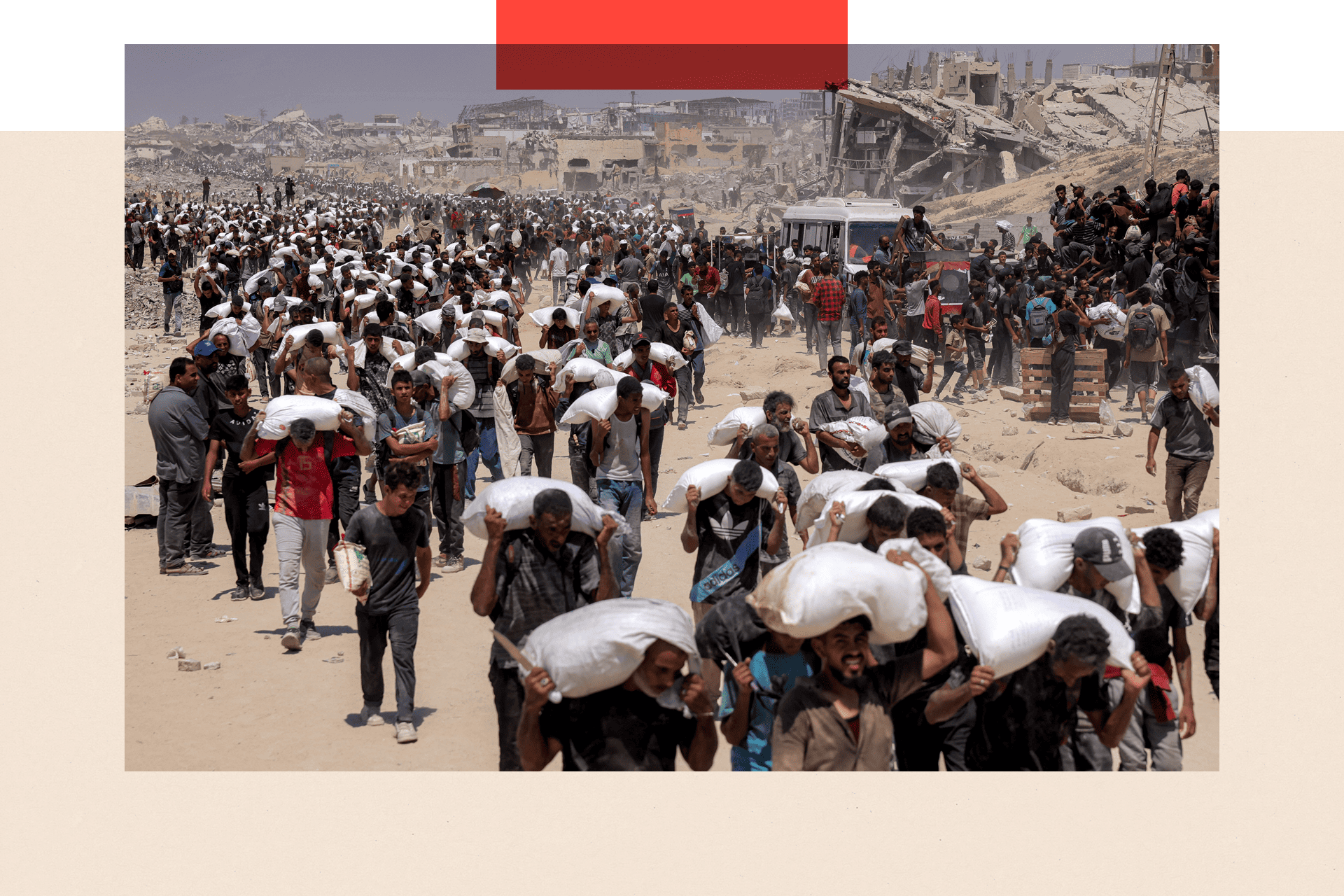 Many lines of people walk with sacks of flour delivered by trucks carrying humanitarian aid 