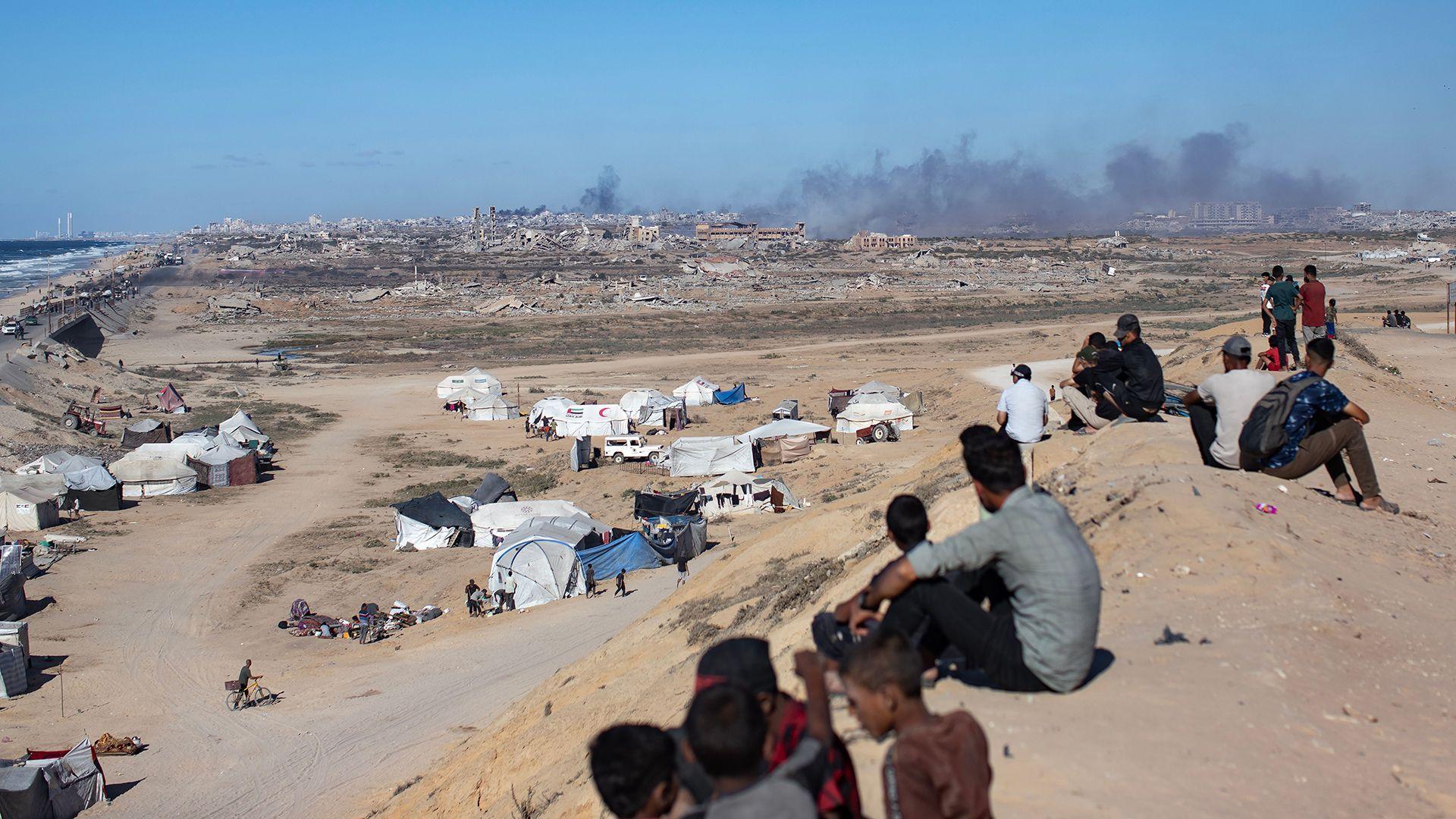 Palestinians watch as smoke billows after Israeli airstrikes on the coastal area, northwest of Nuseirat refugee camp, as they are displaced southward from Wadi Gaza following an Israeli announcement of the closure of Al-Rashid road toward the north, Gaza Strip, 1 October 2025.