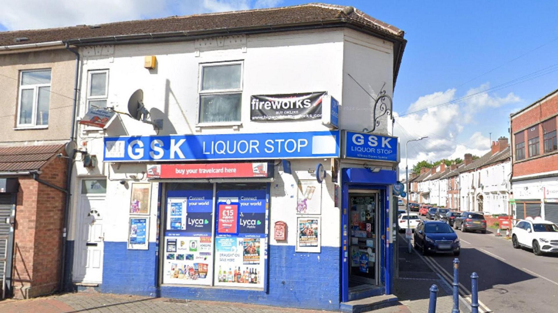 A corner shop painted blue on the outside, with a blue sign with white lettering that says : GSK liquor Stop.