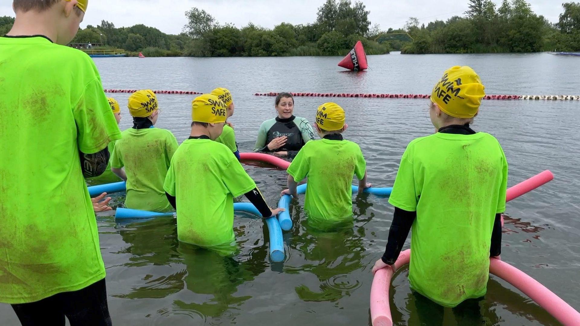 Children and Instructor in the lake with noodle floats 