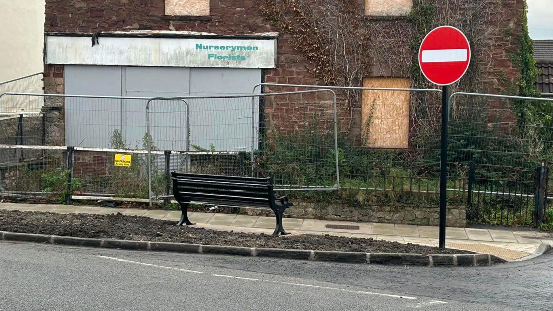 A bench facing a derelict building.