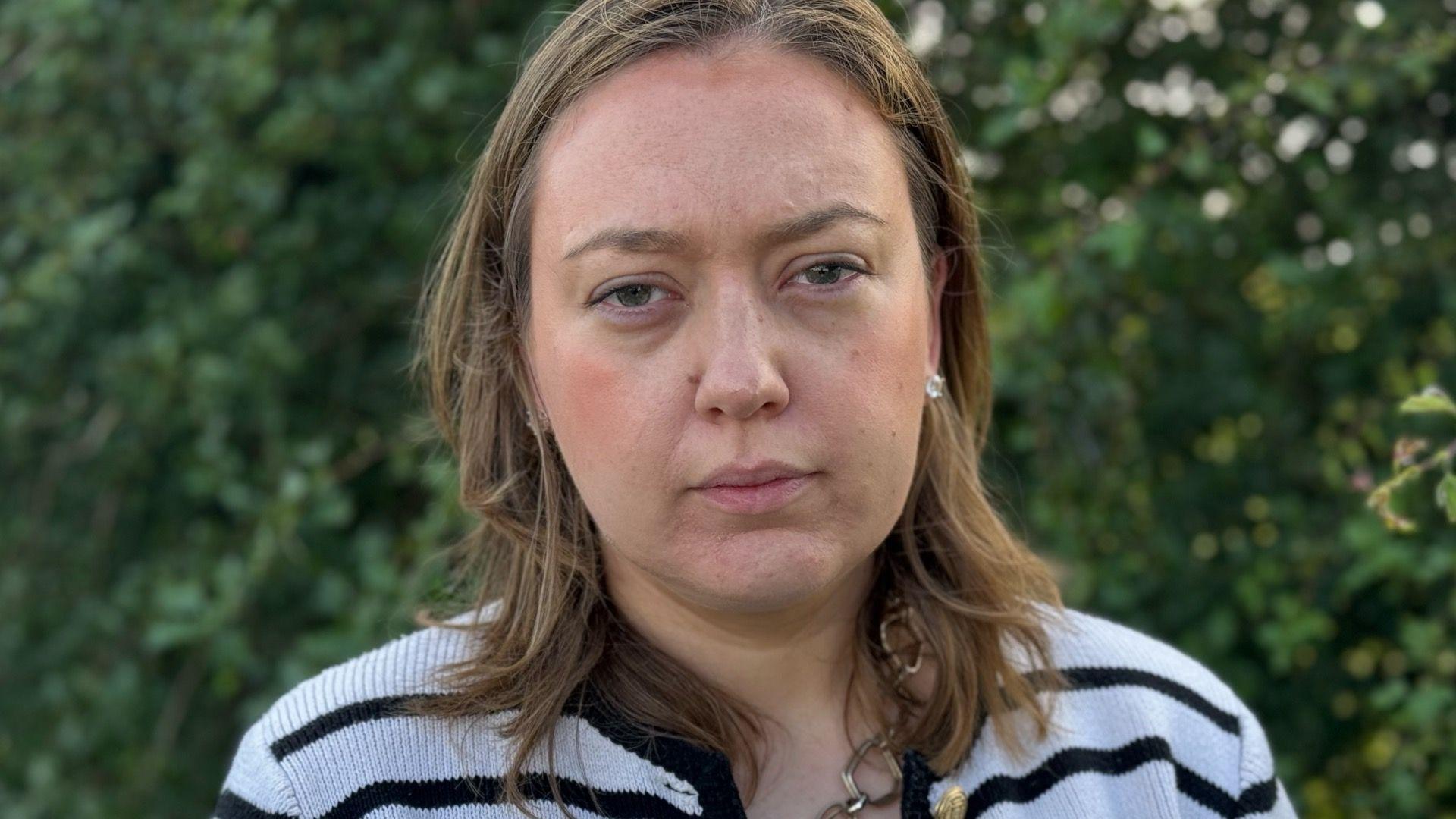 A woman with brown shoulder-length hair and a stripey top 