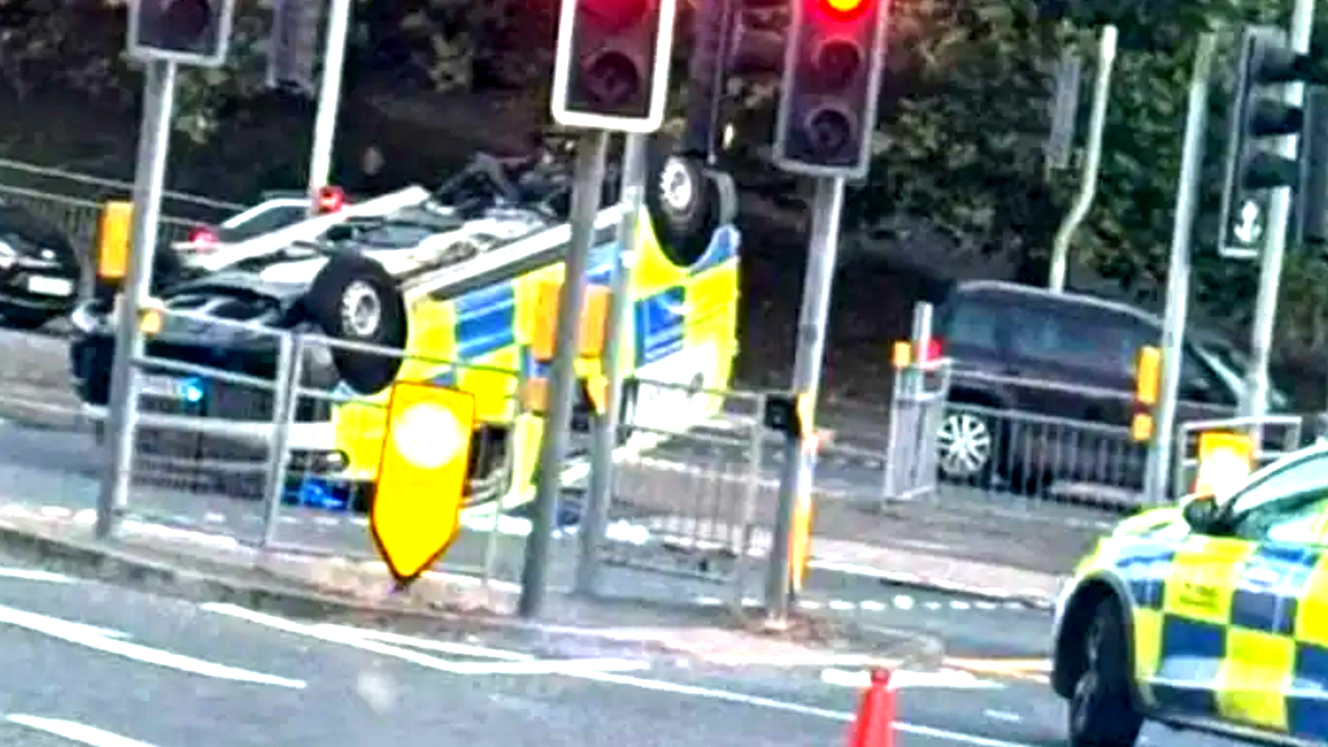 Essex Police car on its roof on a busy road with traffic lights