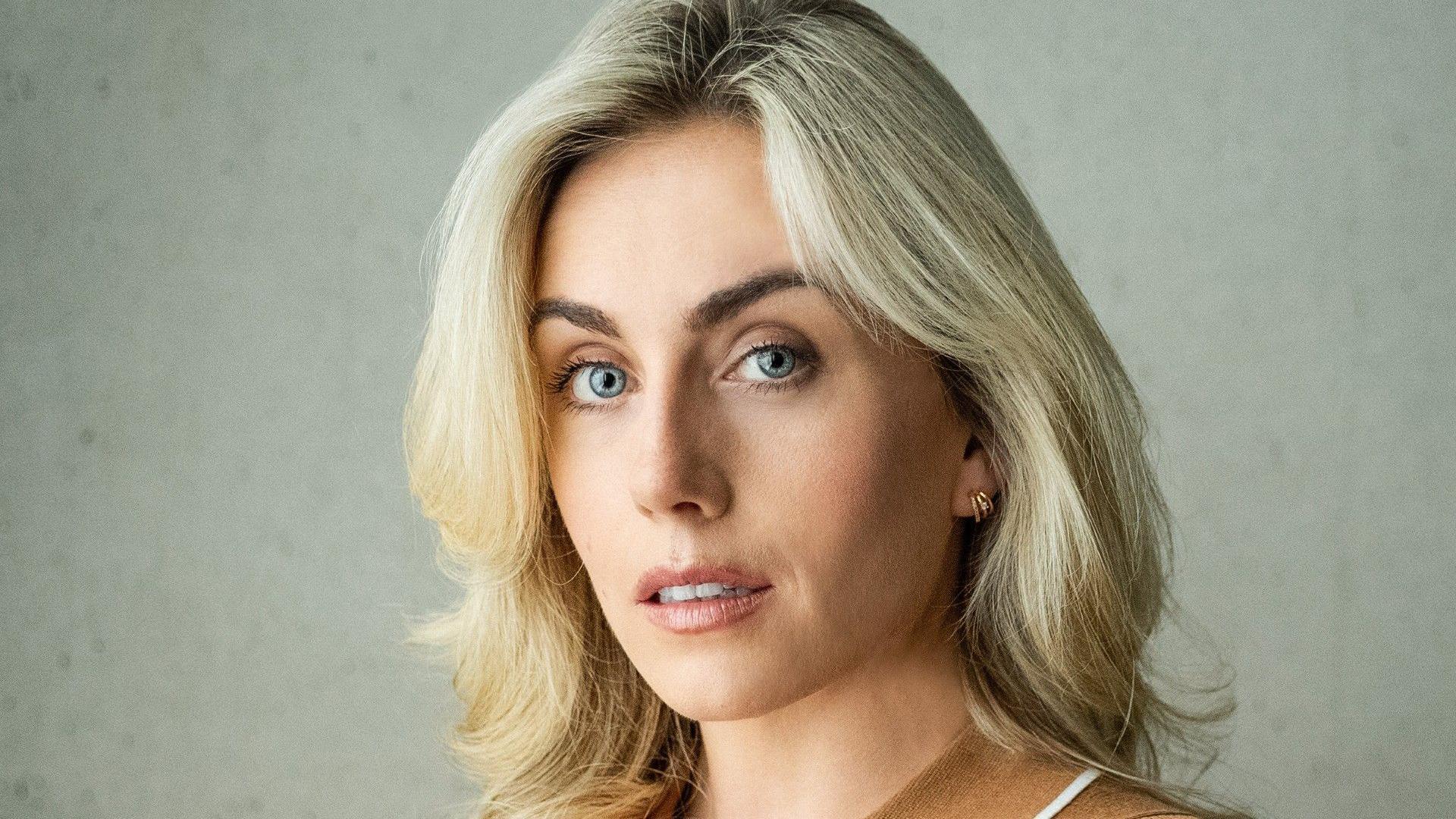 A headshot of Gigi Neil, with long blond hair, looking at the camera