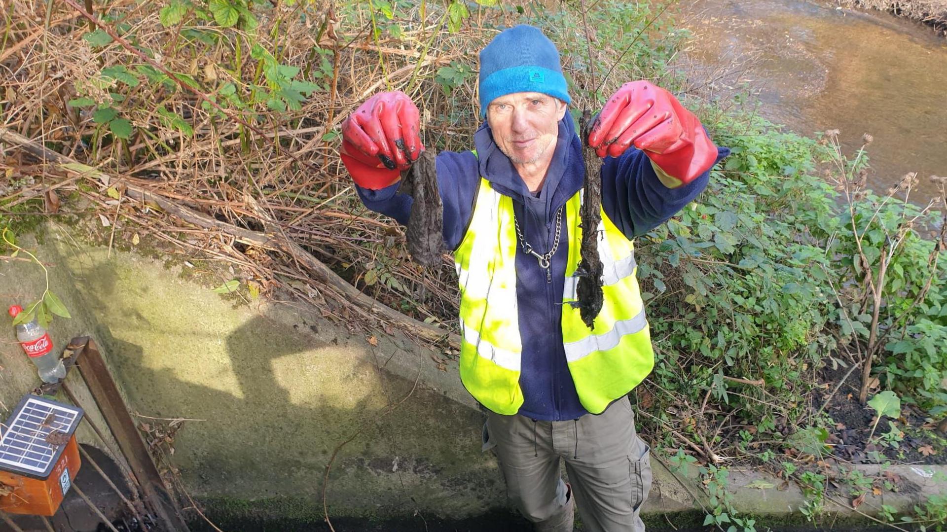 Ben Morris holding sewage while wearing gloves and  a yellow high viz jacket