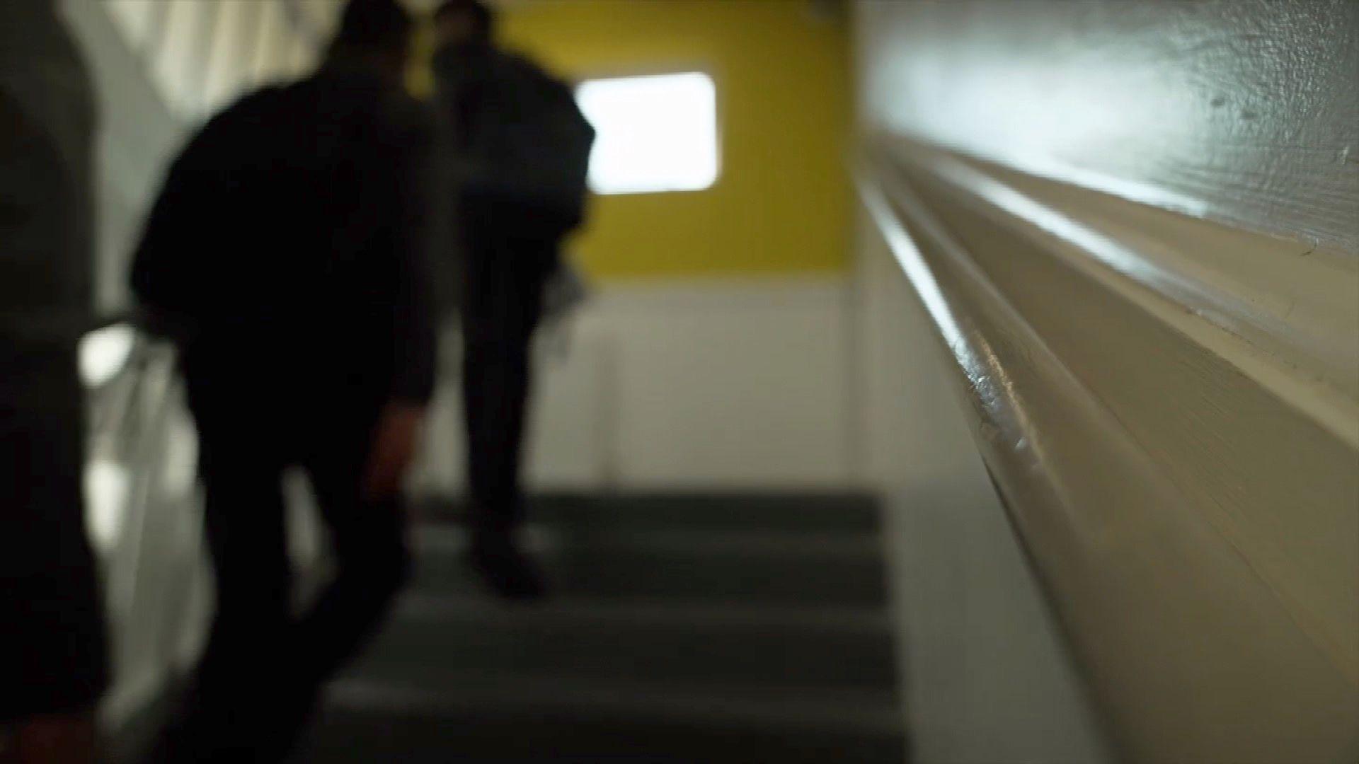 Blurred image of students walking up a staircase inside a school
