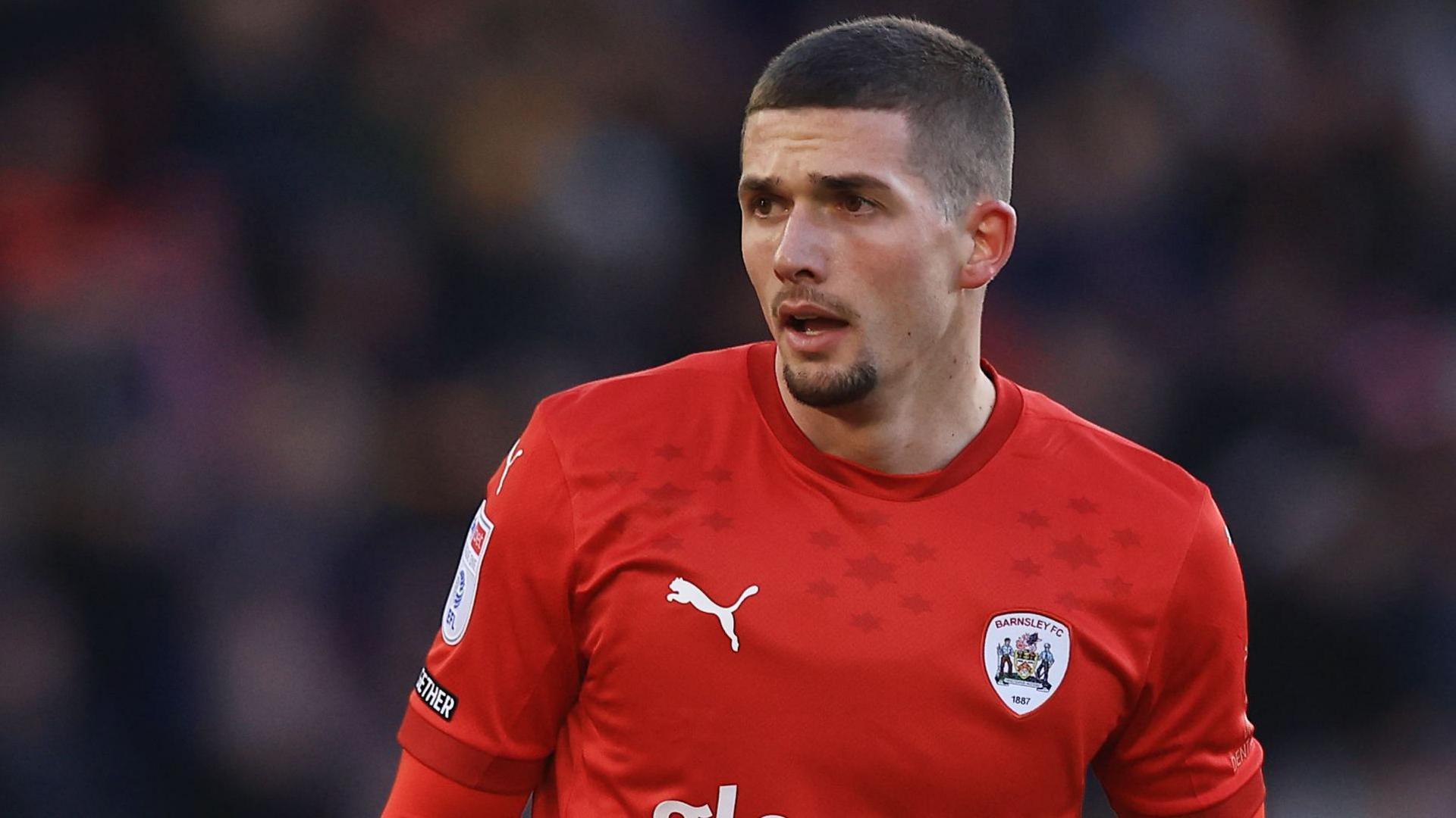 Max Watters in action for Barnsley. He is wearing a home red shirt.
