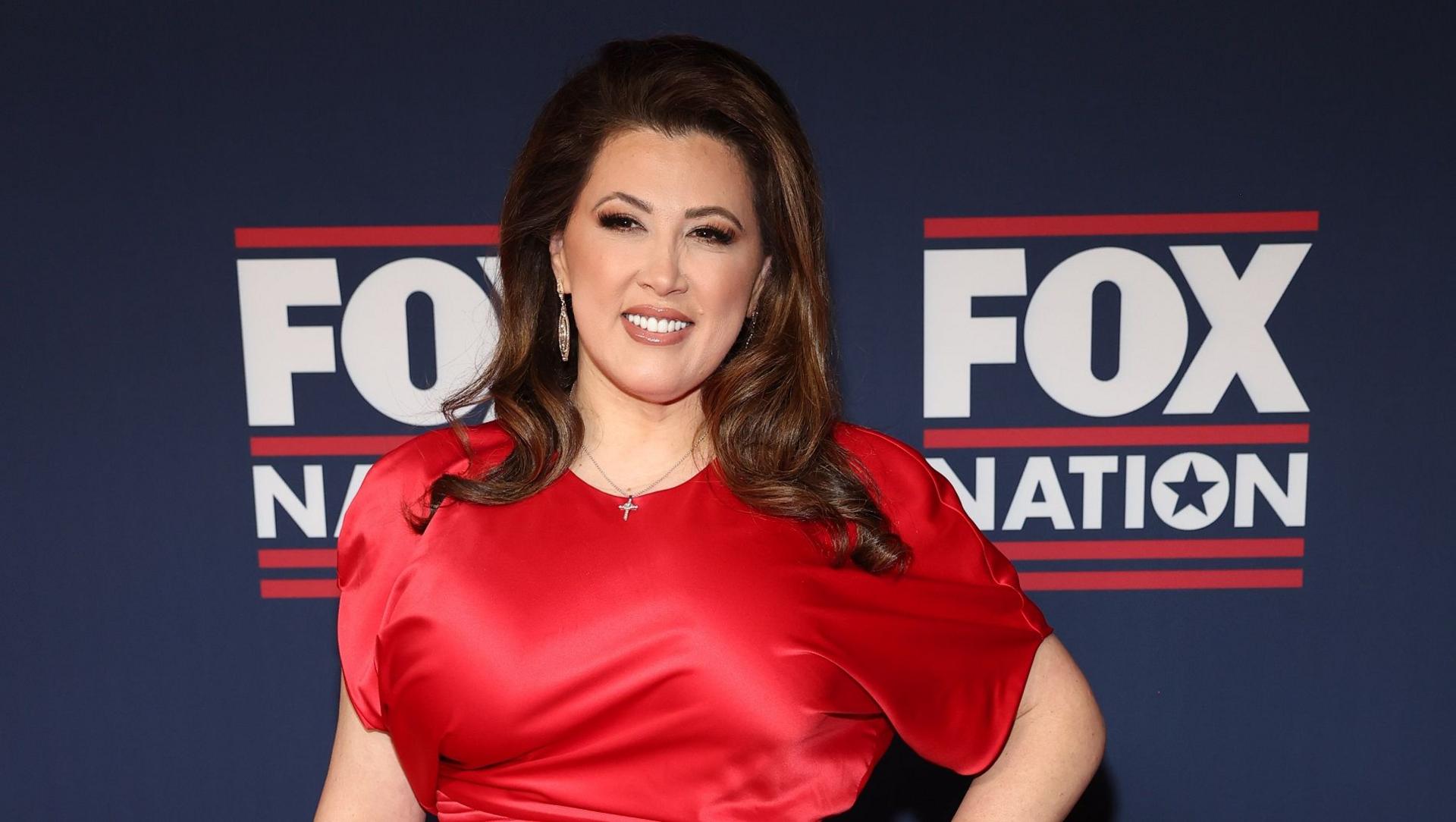 A dark haired woman in a red dress in front of a banner saying "Fox Nation"