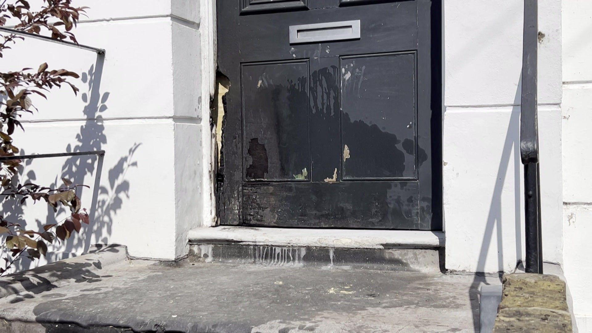 Fire damage on a black door, set in a white building
