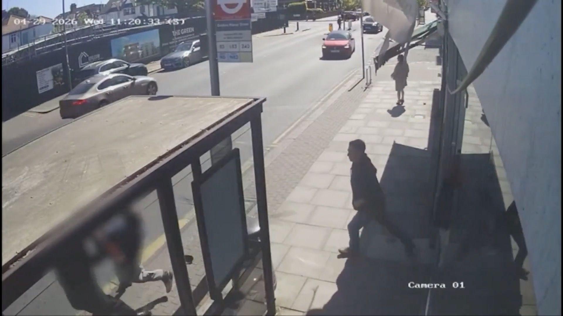 Një imazh statik nga një kamera CCTV që tregon dy burra që vrapojnë pranë stacionit të autobusit dhe Ashkan Asadian që vrapon pas tyre.
