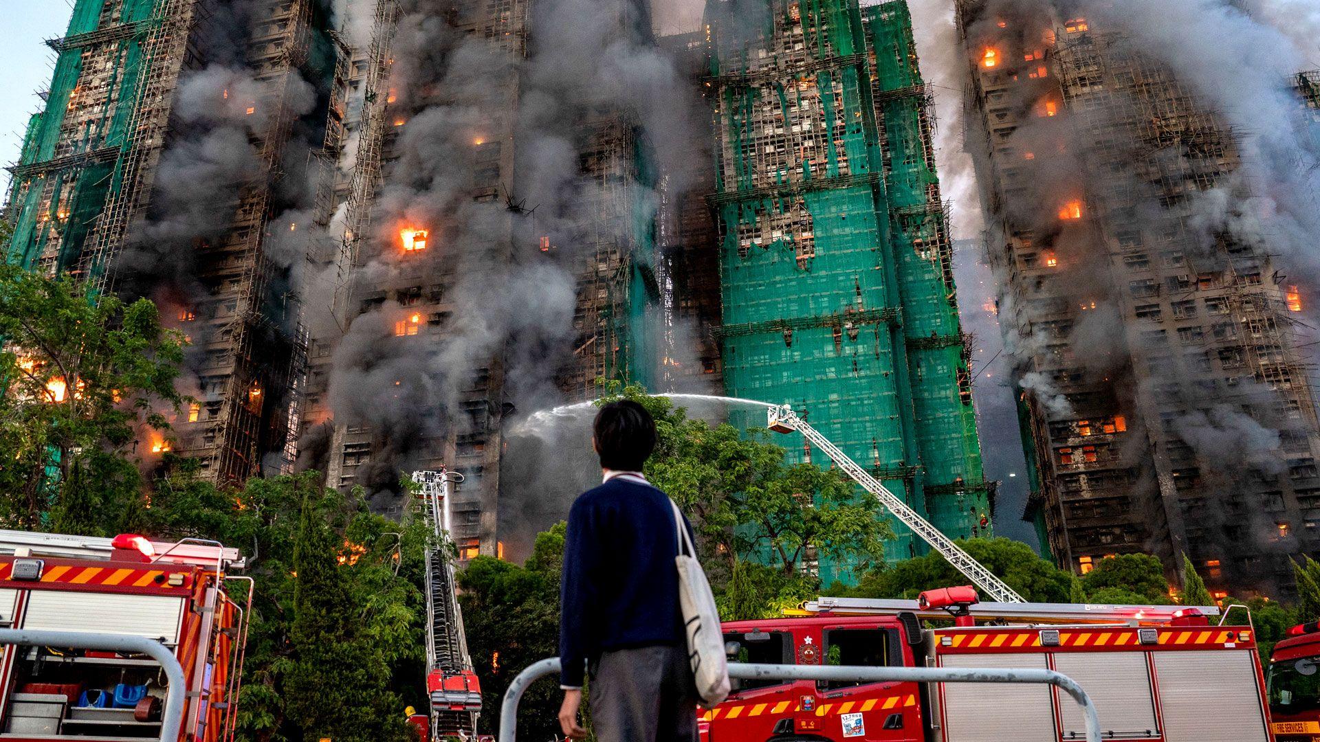 A student watches as smoke and flames rise as a major fire engulfs several residential buildings at Wang Fuk Court
Single use only on this story, can be syndicated