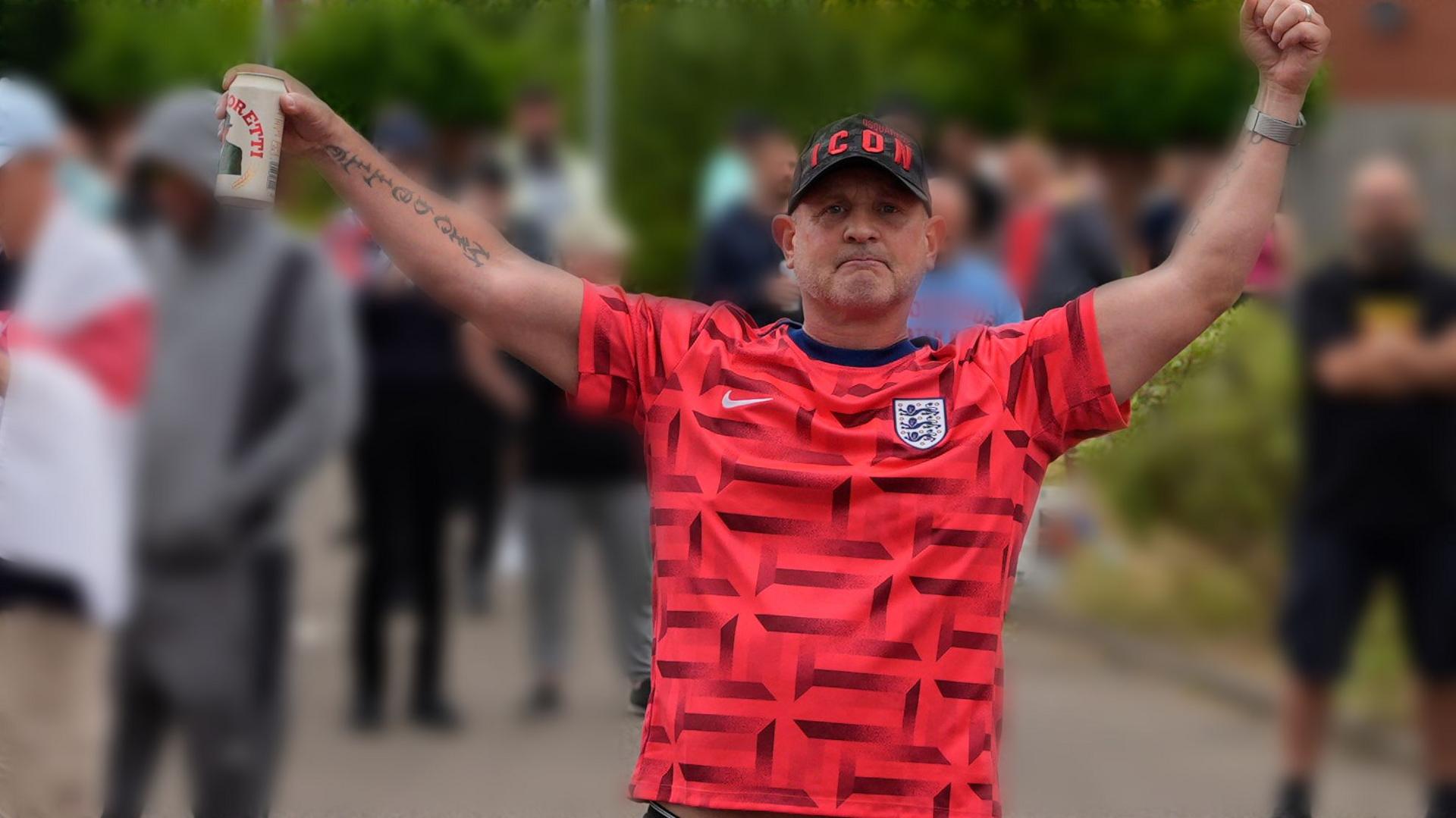 A man in a red shirt holding a can of beer