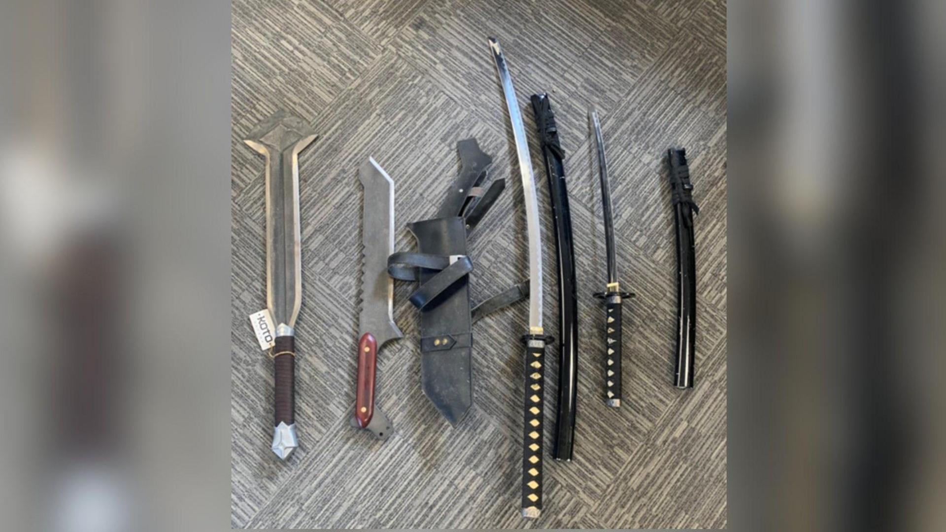 A selection of bladed weapons on a flat surface including a sword
