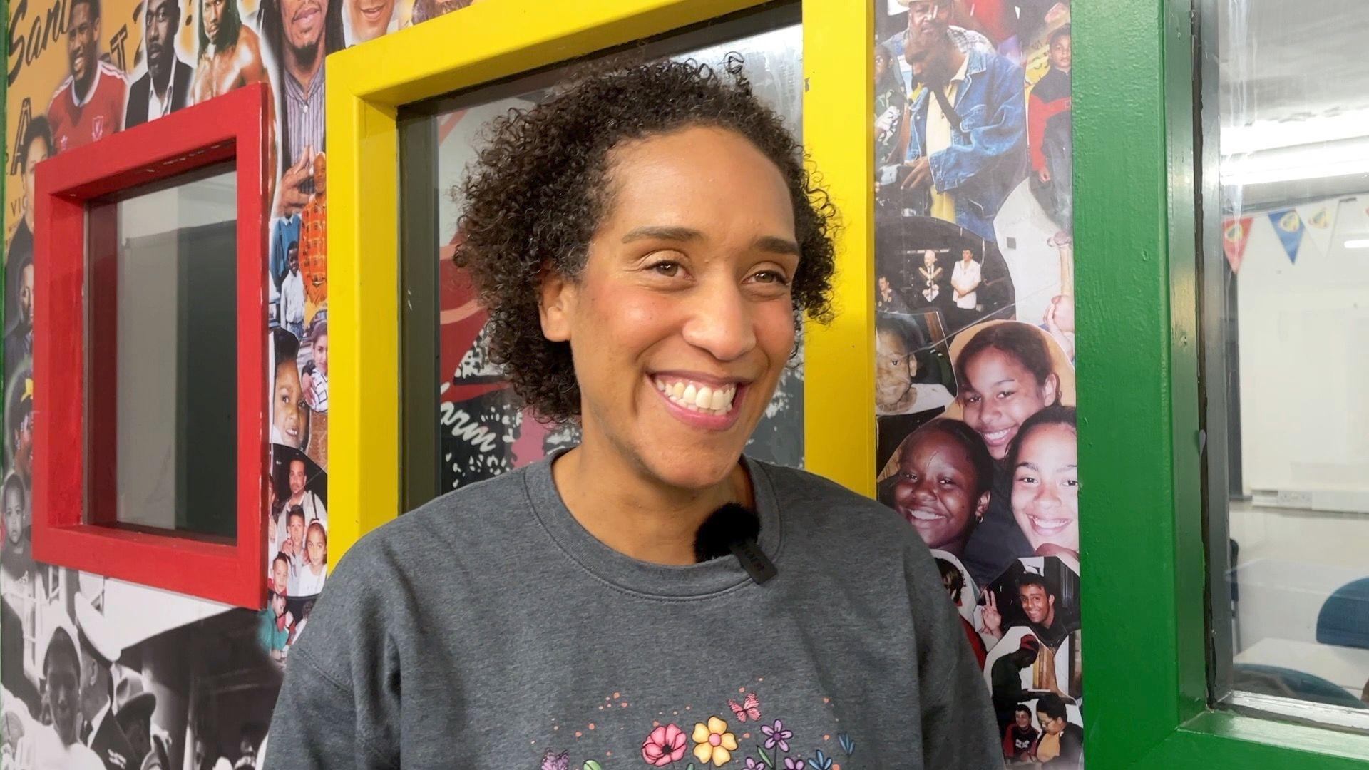 Tricia Arthur-Stubbs smiles for the camera. She is wearing a grey jumper and is excited about the Brave Festival returning as part of Bradford UK City of Culture 2025.