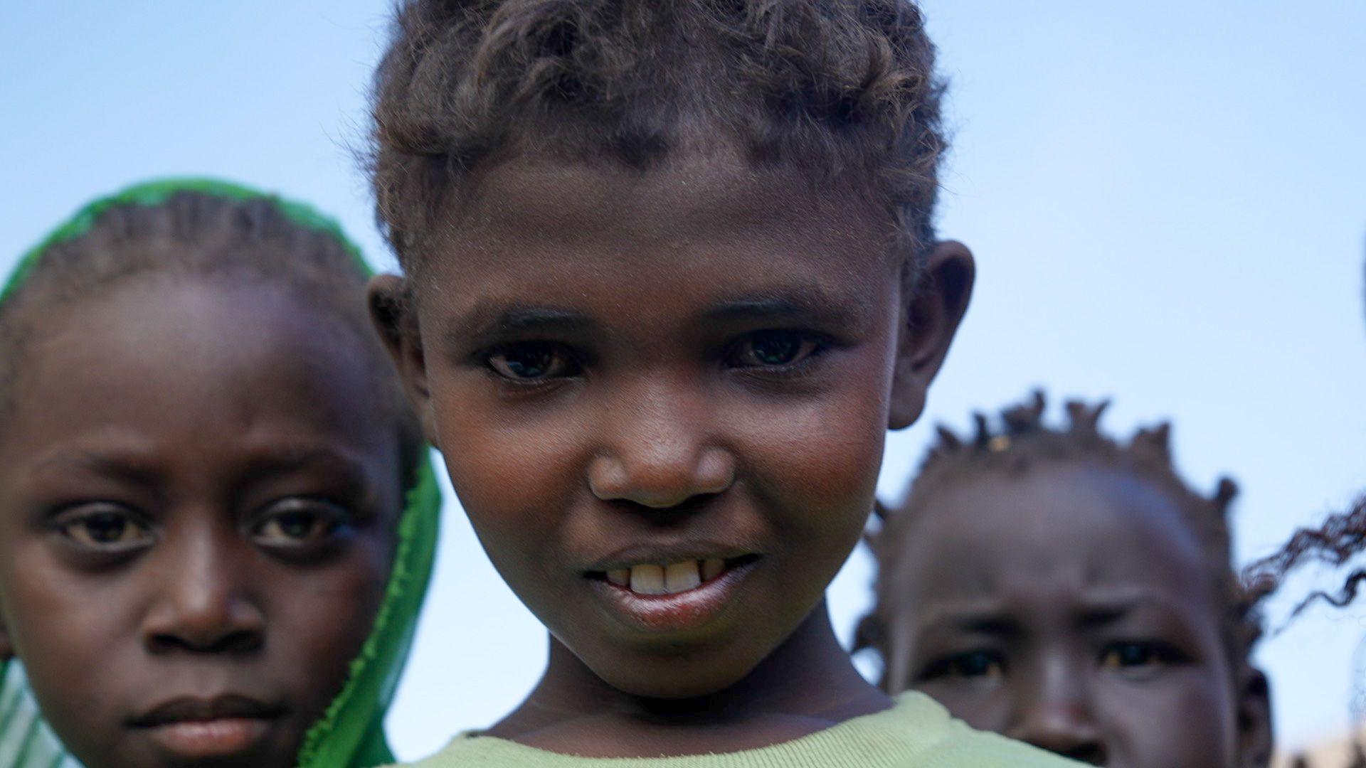 Three children in Sudan stare directly at the camera