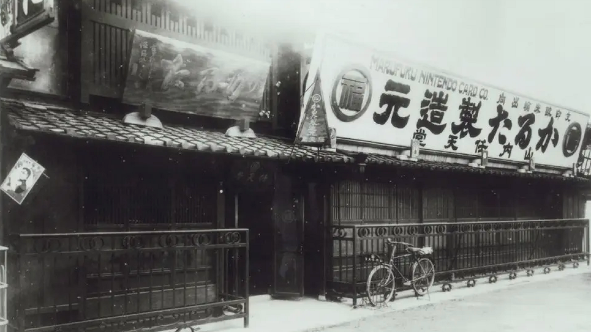 A black and white photo of The front of Nintendo's first store in Kyoto with a bicycle parked outside