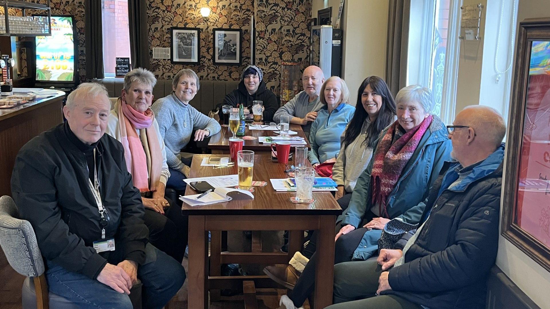 Nine people sit around a table at a pub