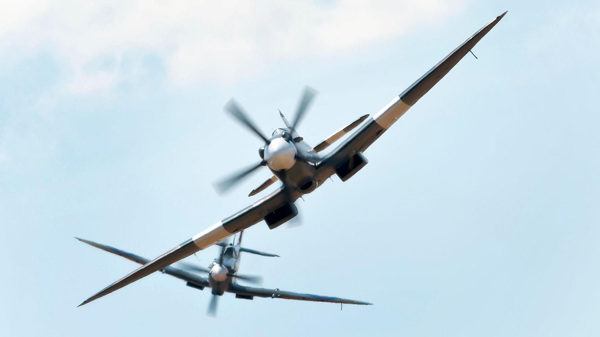Two Spitfires fly in the sky.