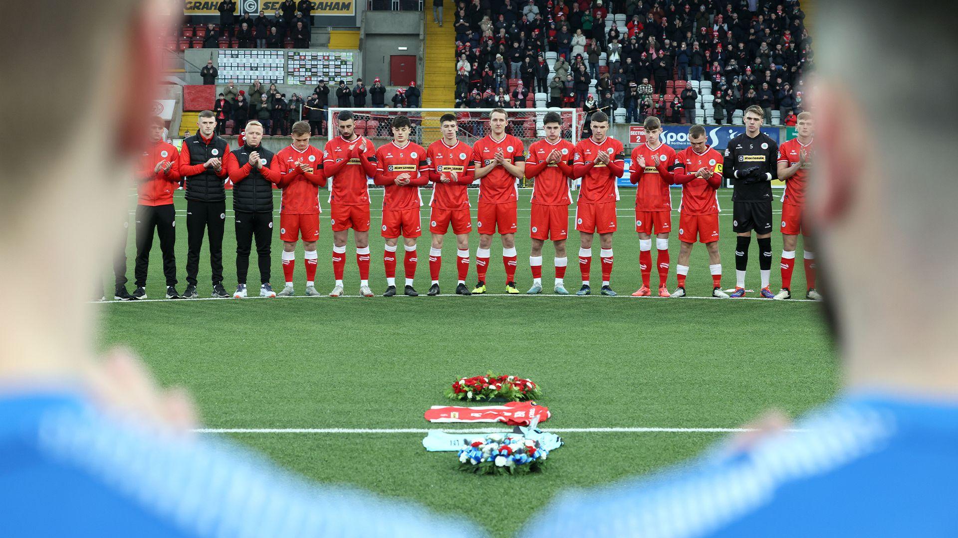 Cliftonville and Banbridge Rangers players observe a minute's applause for Michael Newberry