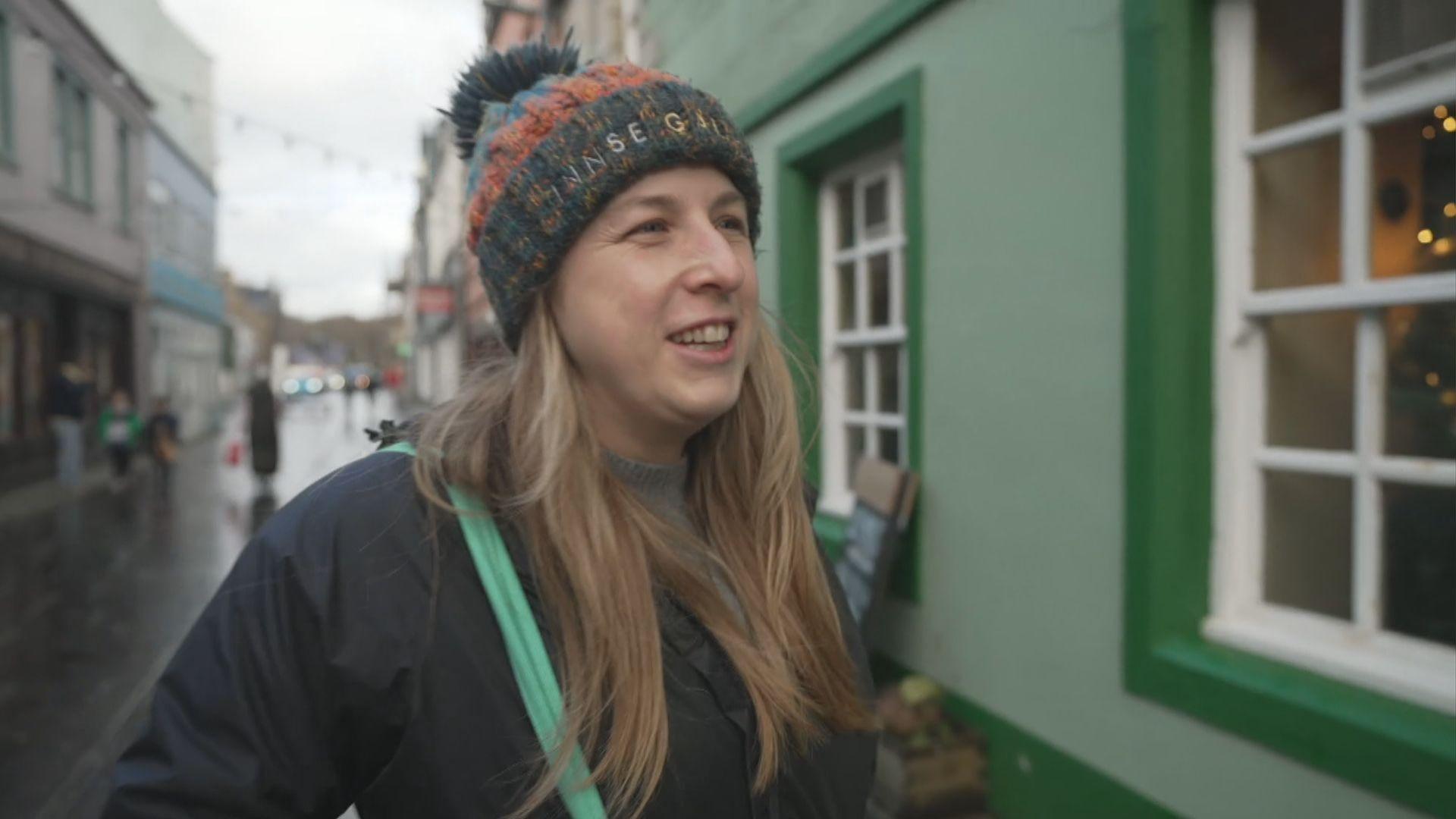 Lizzie Aucott-Hall wearing a winter coat and a beanie hat standing in the street