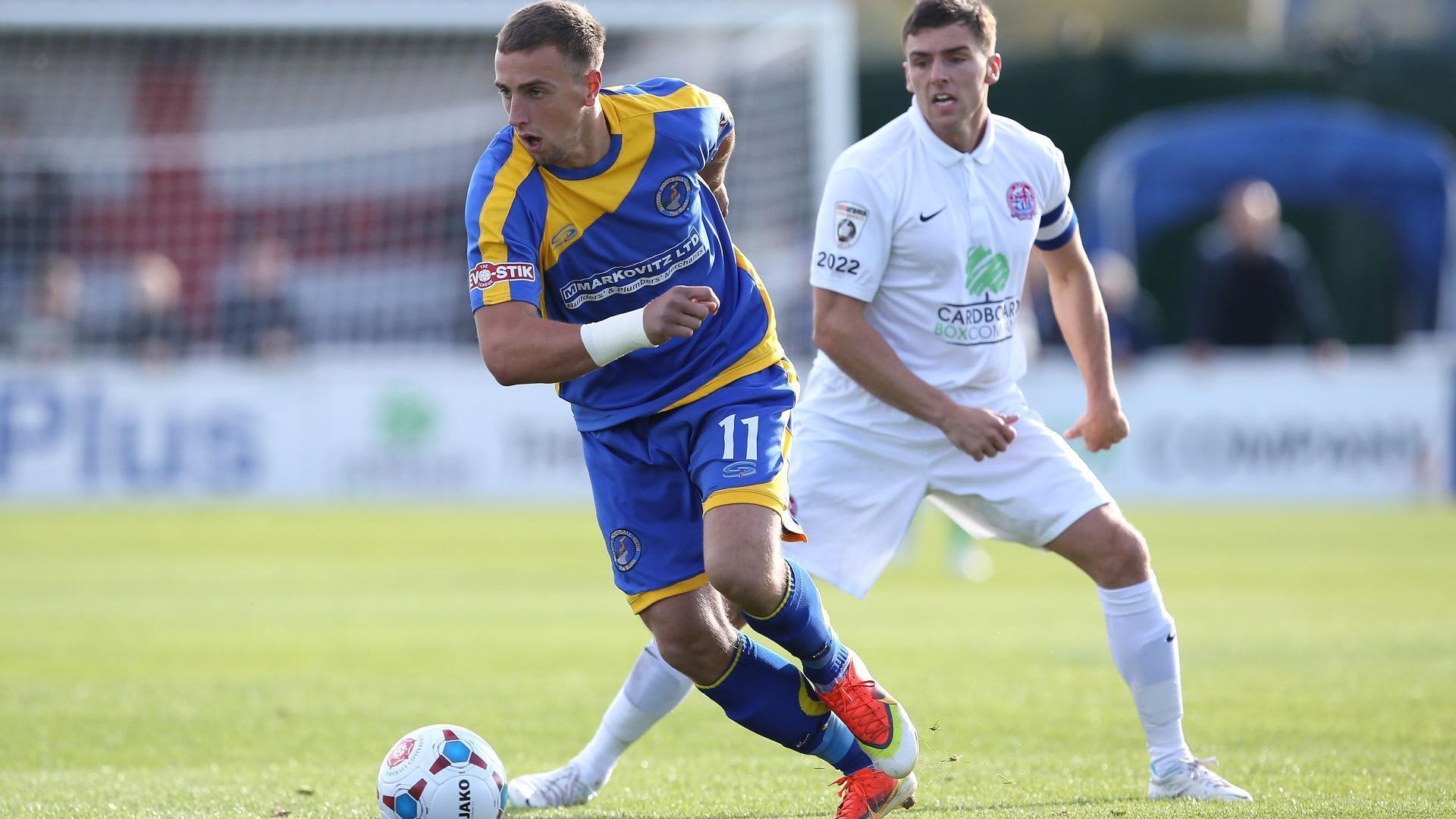 Two footballers, one wearing blue and yellow the other in all white