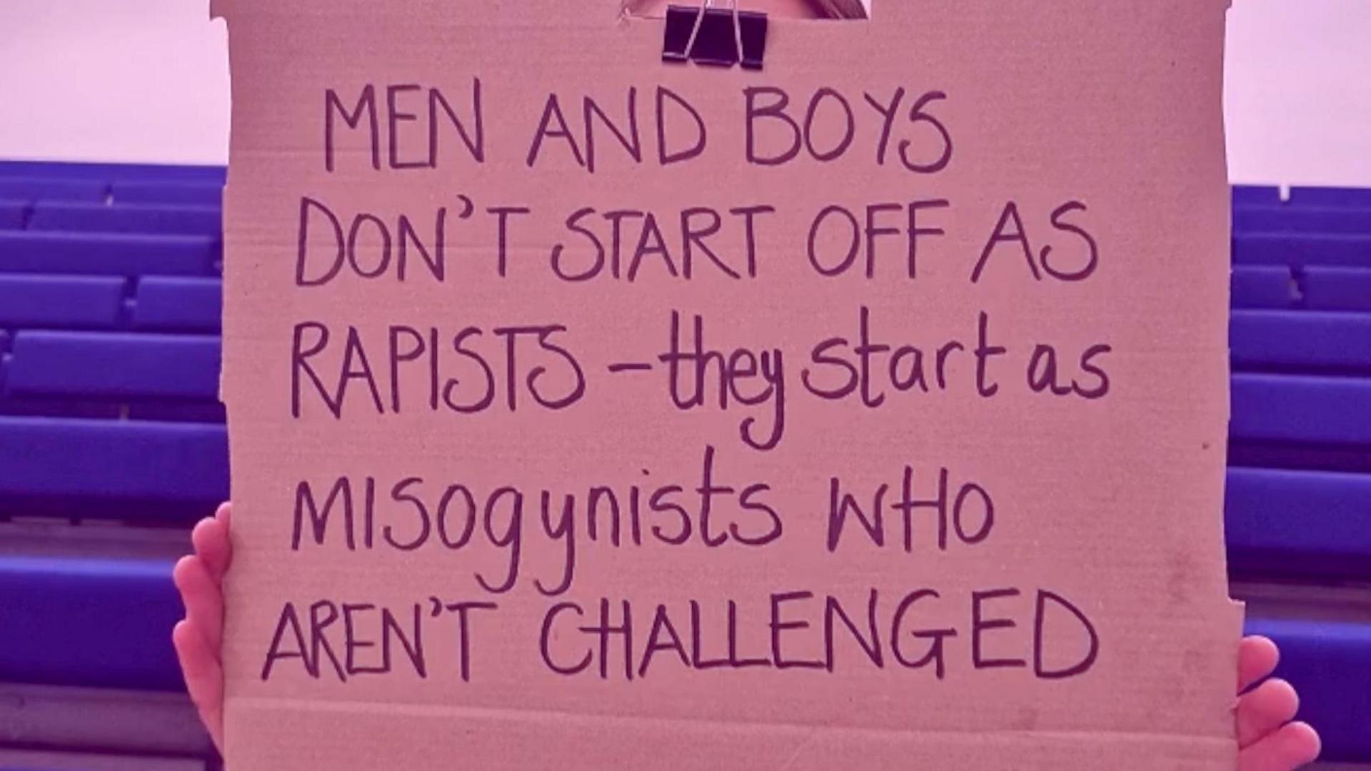 A cardboard motion   is held successful  beforehand   of a girls face, her hands are disposable   connected  the edges. The operation   'Rapists - they commencement  arsenic  misogynists who aren't challenged' is written connected  the motion   successful  achromatic  marker pen.