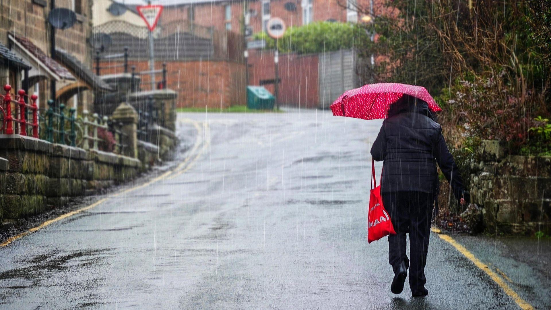 A view of heavy rain and flooding in a rural area of the UK, with water covering roads and fields.