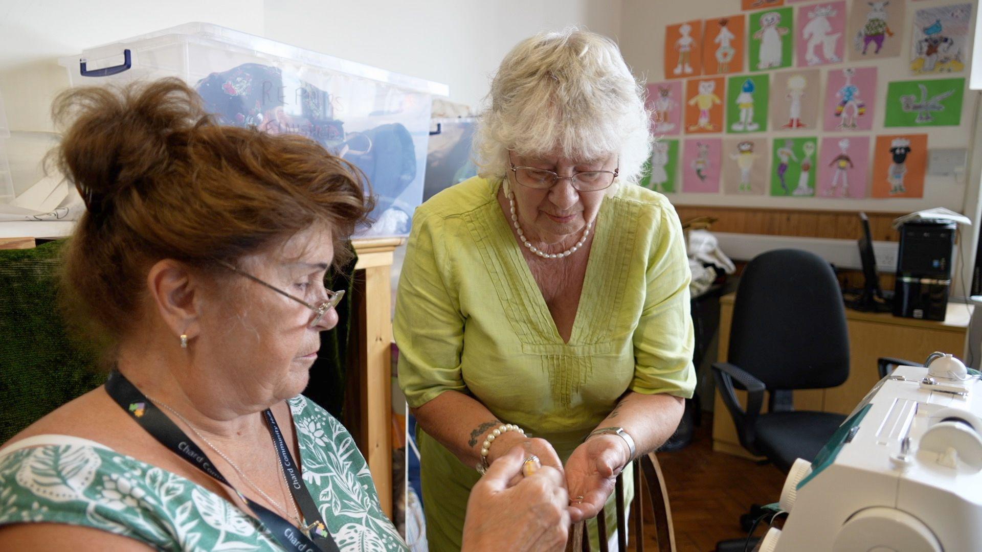 A woman helps someone using a sewing machine at Chard Community Hub