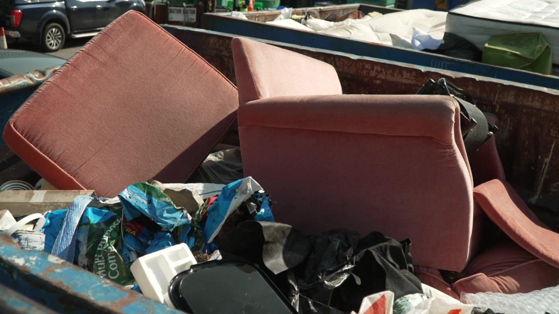 Sofa and cushion in a skip at the recycling centre