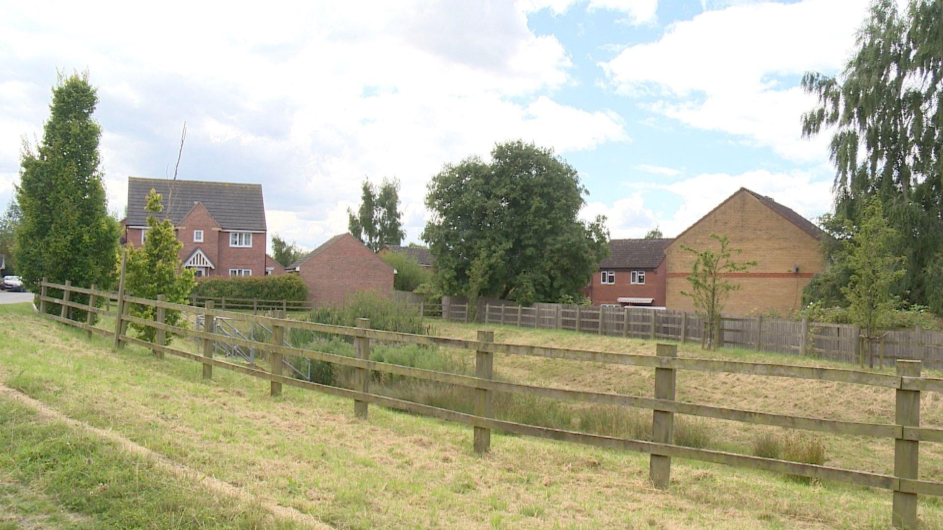 A picture of a balancing pond and fence on a new-build housing estate 