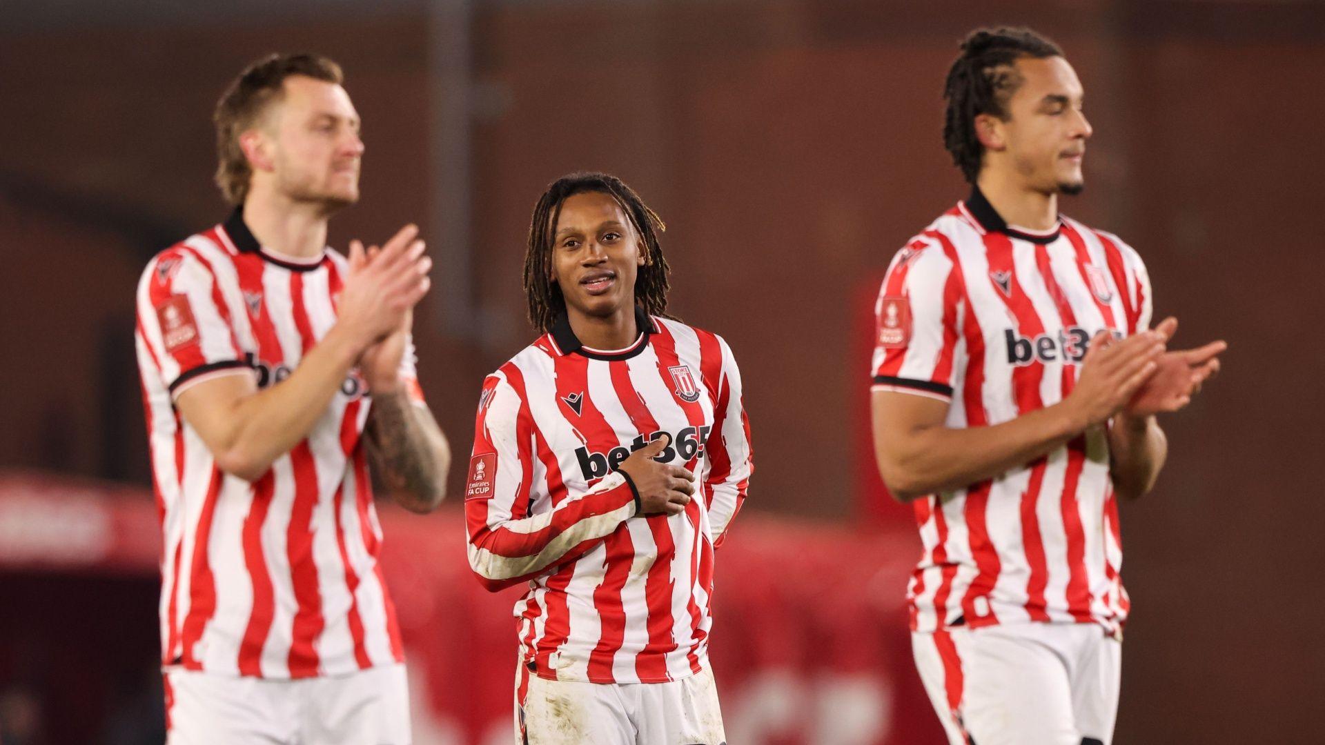 three stoke city players in their red and white striped kits clap, with the middle one putting his right hand to his midriff.