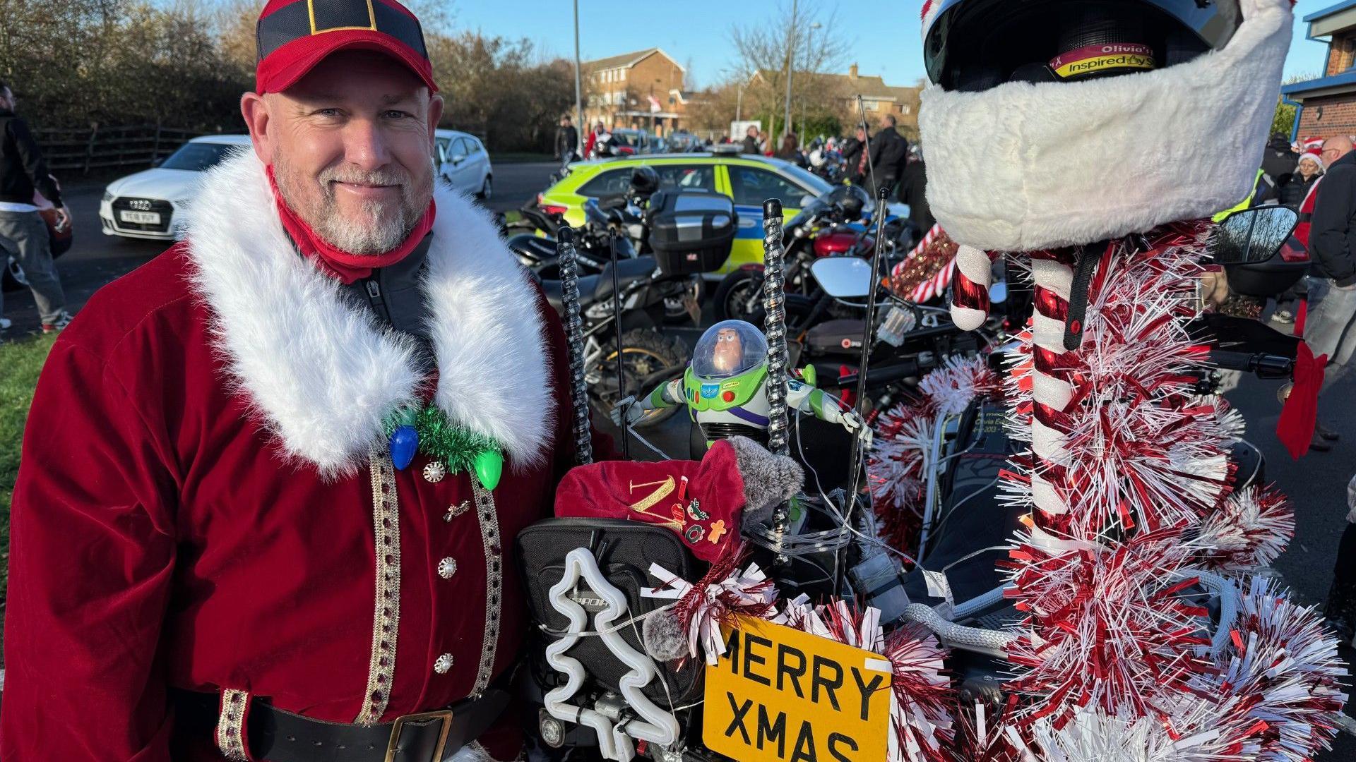Mark Spindley is the ride organiser, he's dressed as Father Christmas and his bike has red and white tinsel on it with a Merry Xmas number plate