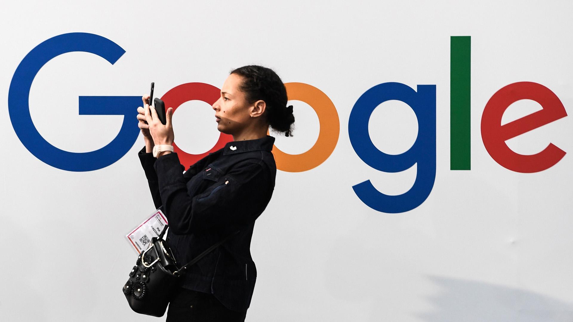 A woman takes a selfie by a Google sign