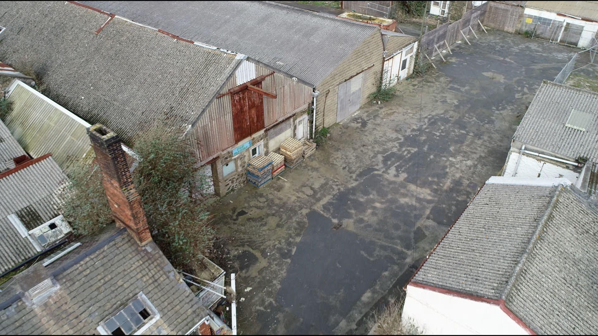 A number of grey derelict parking sheds from the air.