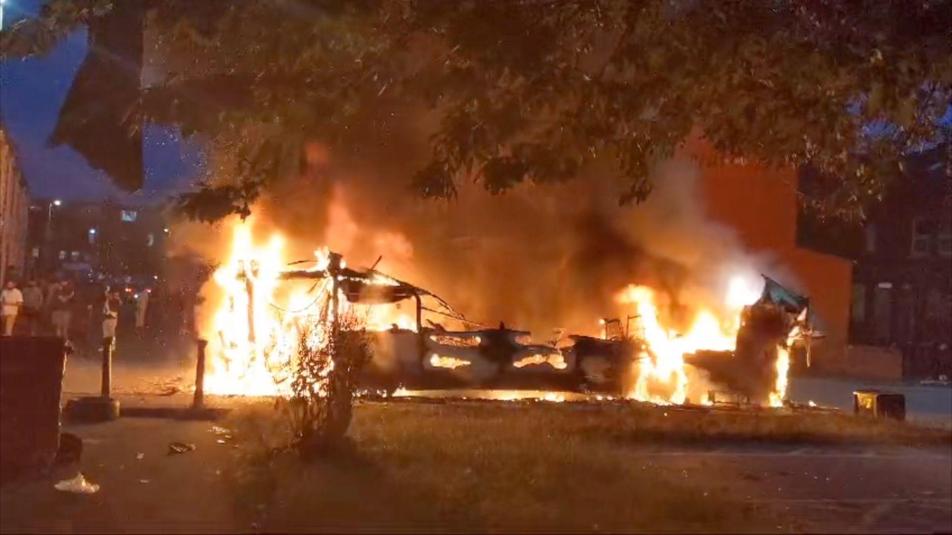 A double decker bus engulfed by flames and smoke