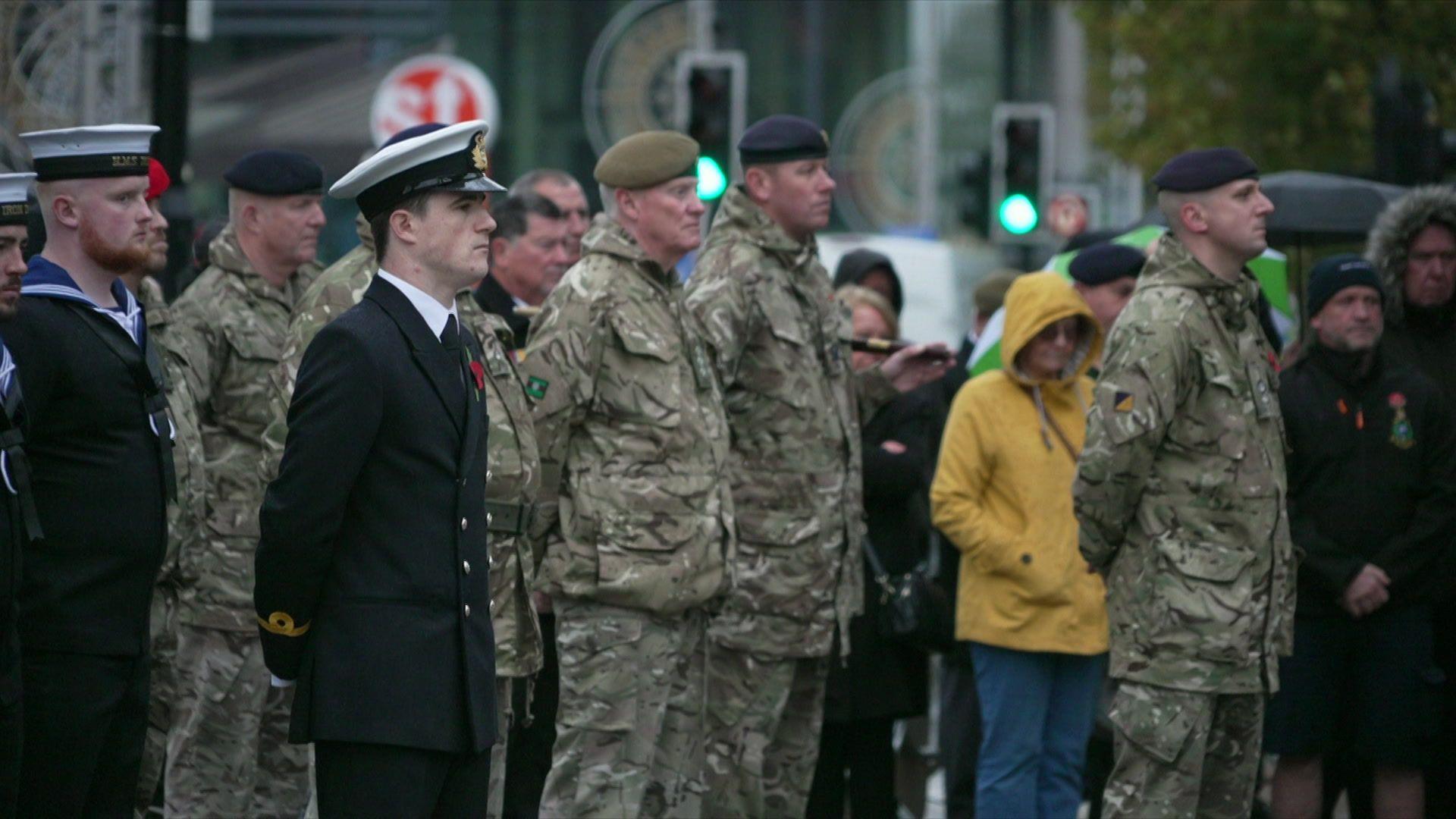 People dressed in military uniform observing a two-minute silence at the Cenotaph in Hull. There is also a crowd of onlookers in the background.