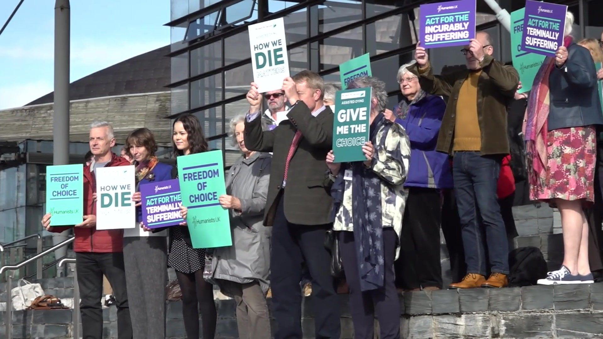 Protesters stood on the slate steps outside the Senedd, holding banners saying "Freedom of choice", "How We Die Matters", "Give Me the Choice, and "Act for the Incurably Suffering". 