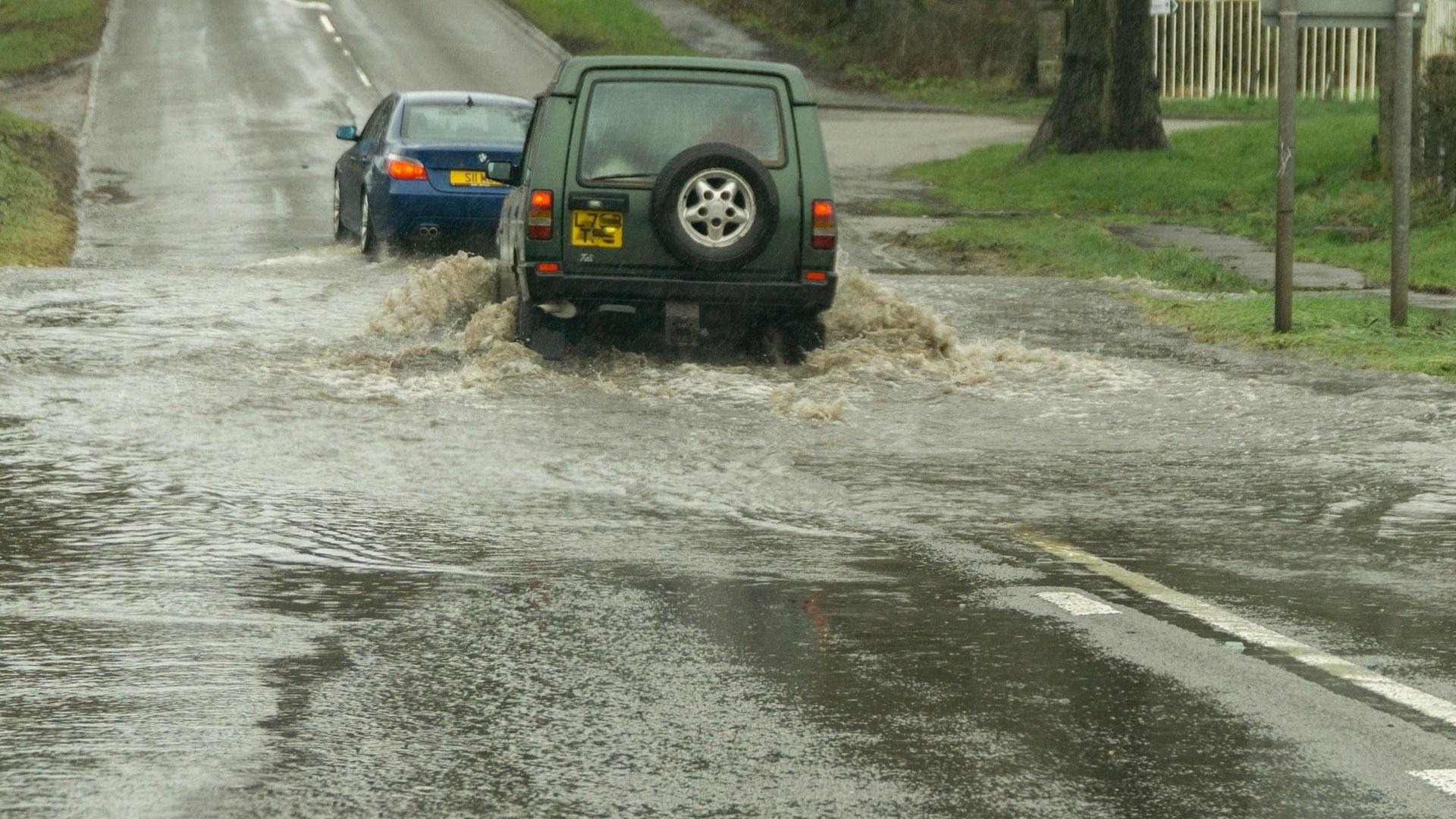 Two vehicles driving on a flooded road