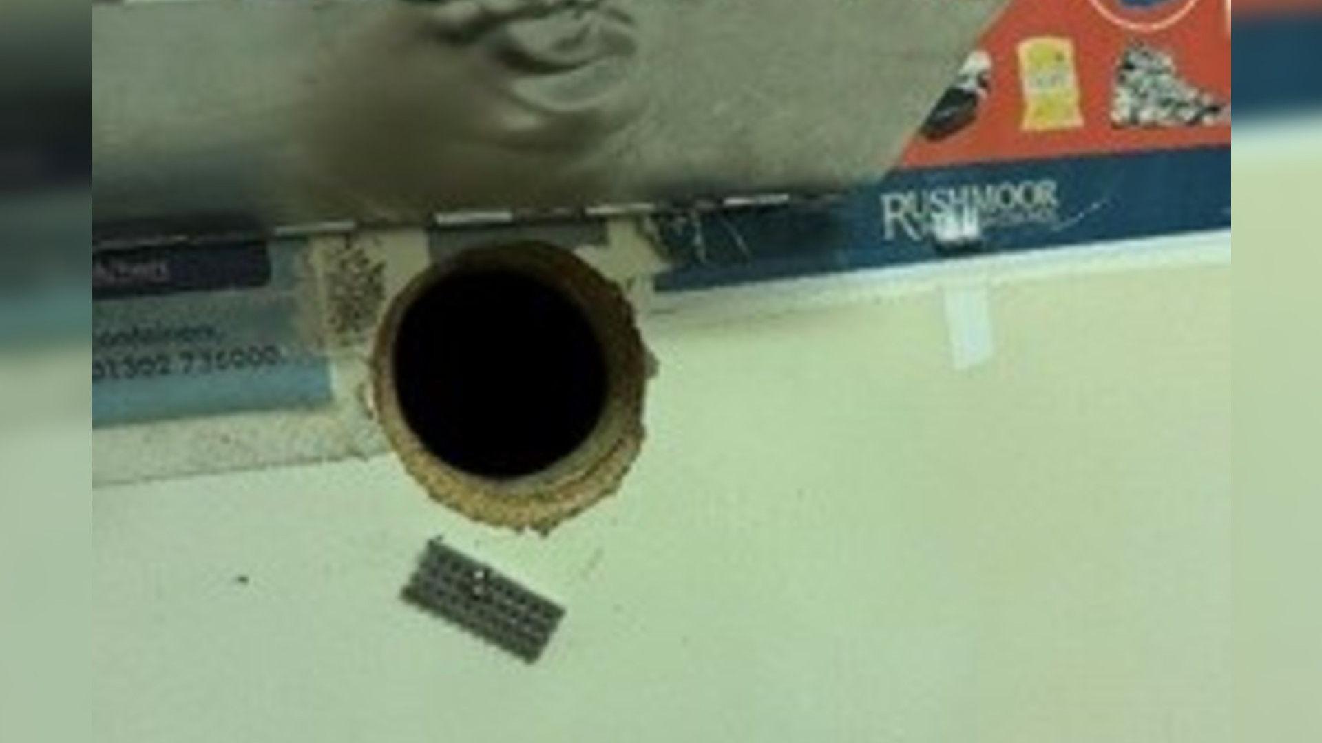 A round hole cut into a wall with a metal cover. 