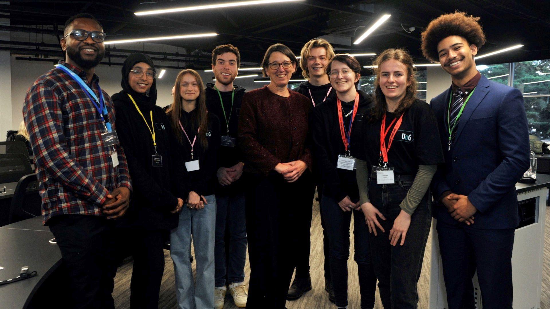 A group of mostly young people looking at the camera smiling with lanyards on at the opening of a new cyber and digital building at the University of Gloucestershire