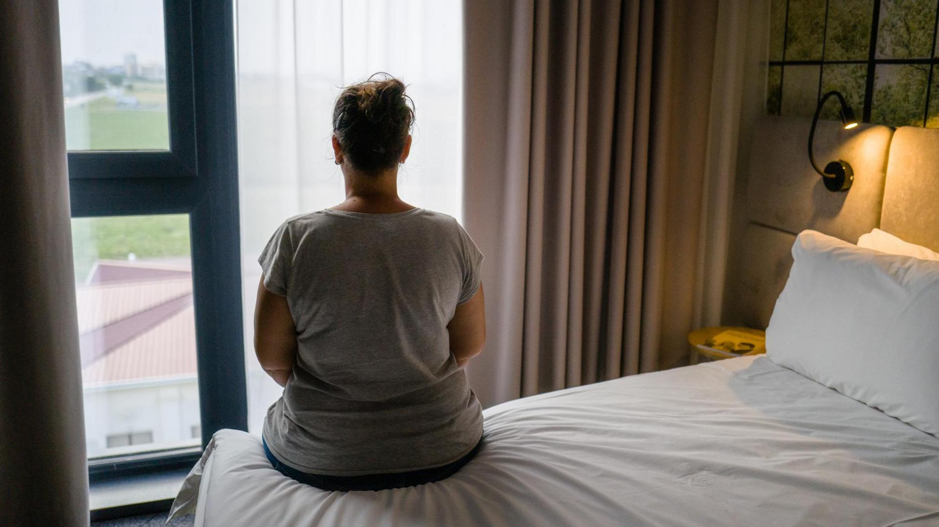 Woman sitting on hotel bed