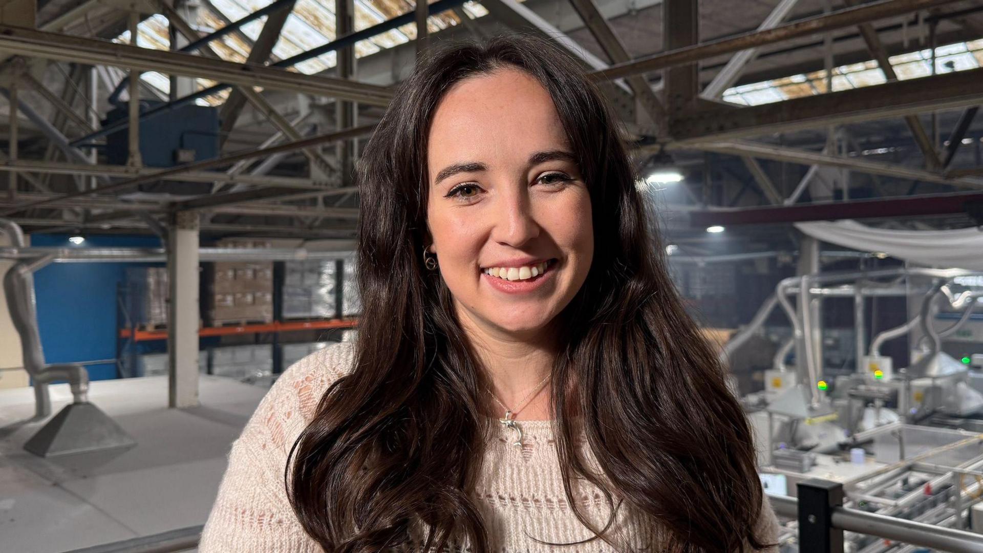 Presenter Megan McCubbin with long dark hair and wearing a white number smiling at the camera.