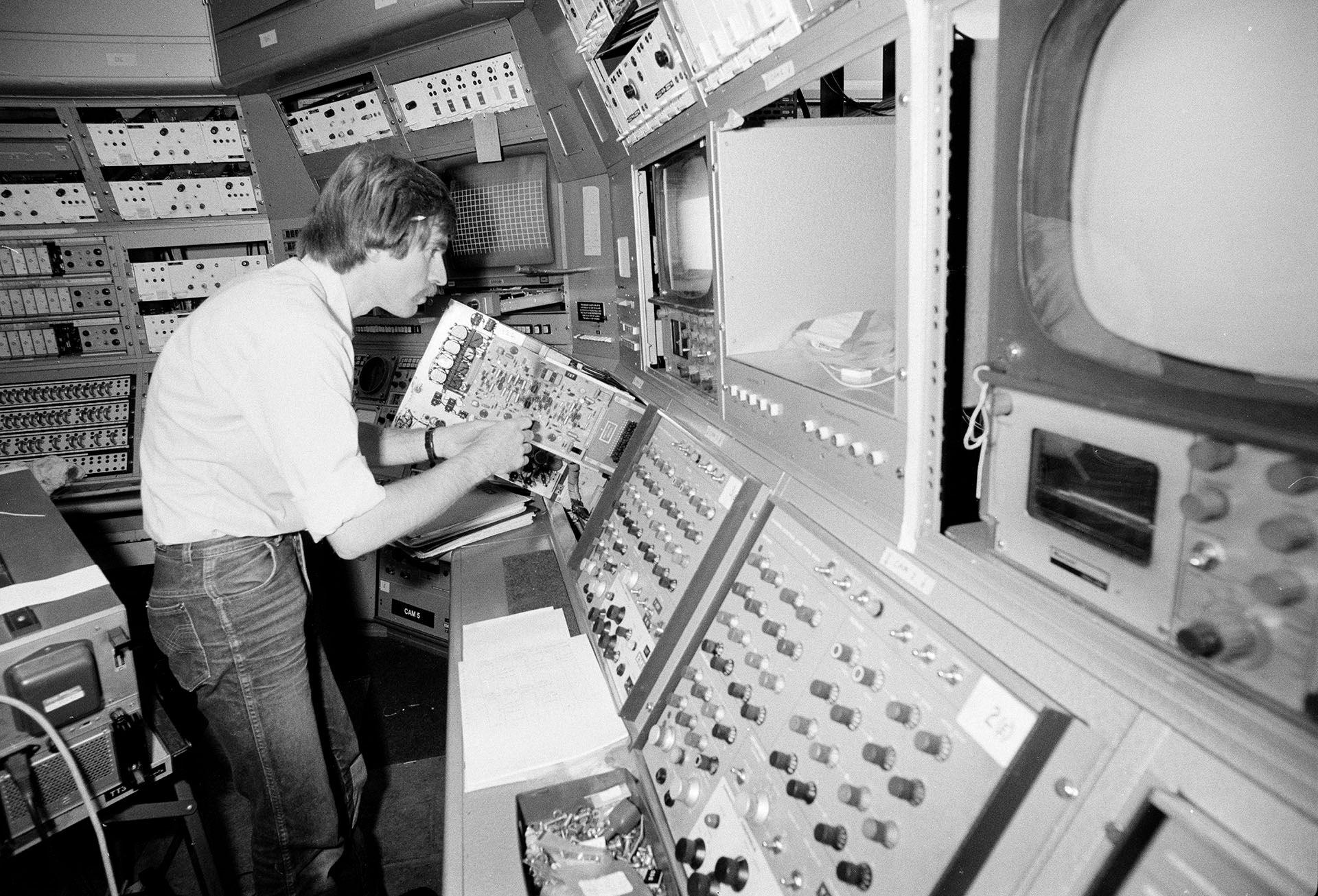 a black and white image of a man inspecting circuity in a director gallery