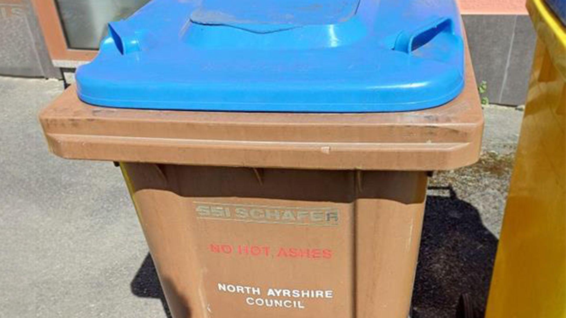 A brown bin with a blue lid, with North Ayrshire Council written on the bin.