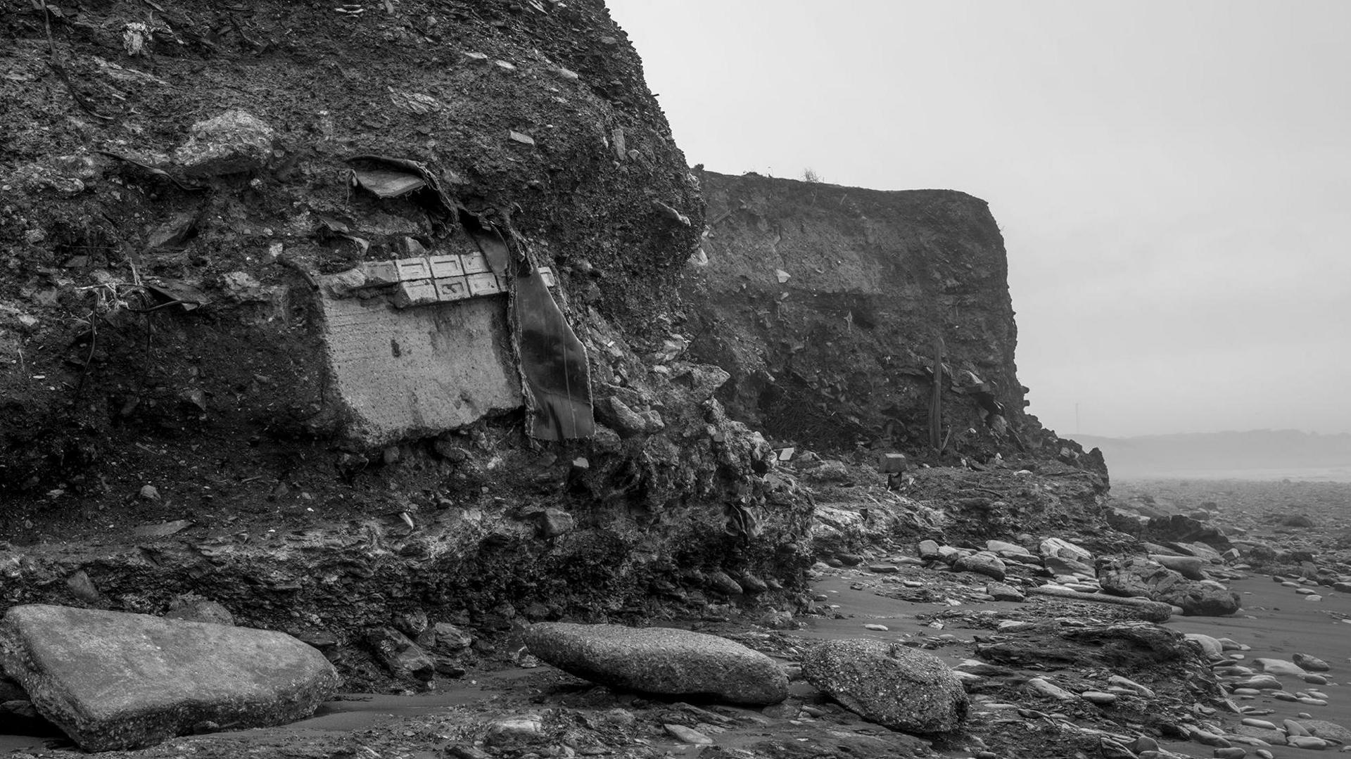 A black and white shot of a cliff with items falling from it 