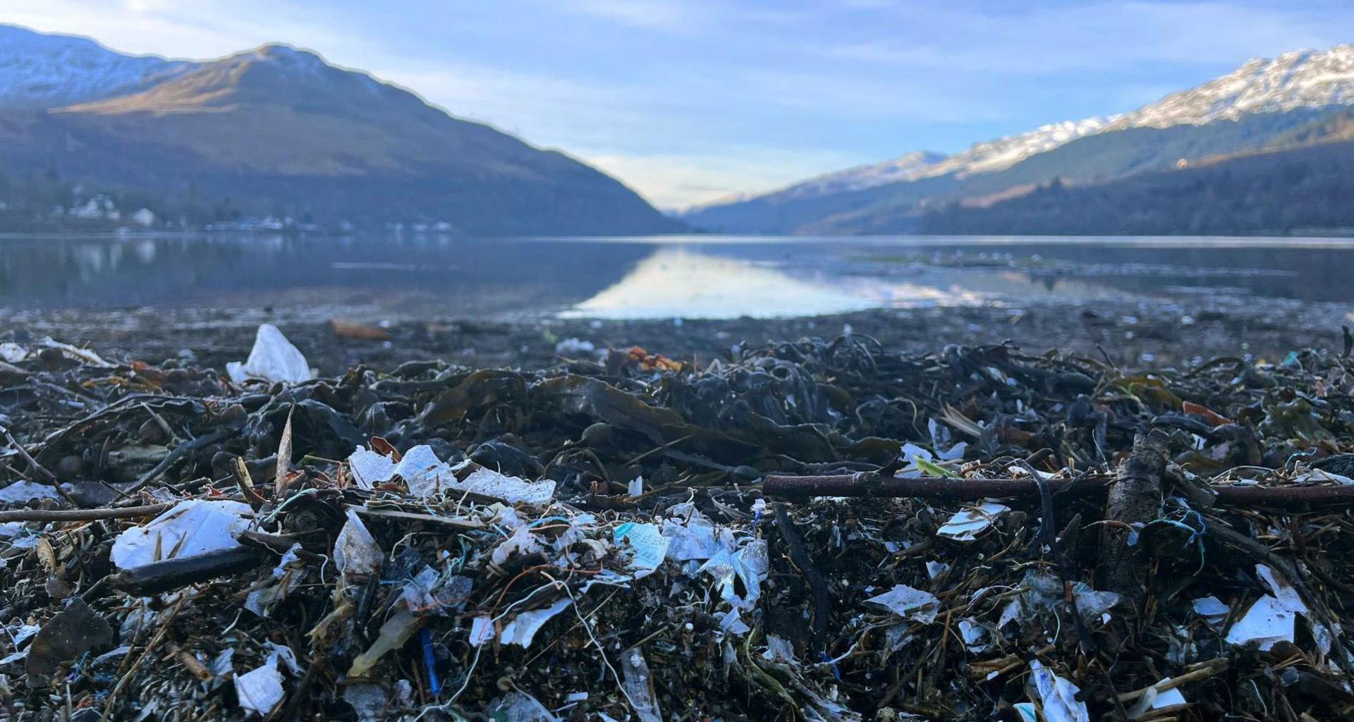 Marine litter sink on the banks of Loch Long at Arrochar. There are snow-covered mountains surrounding the loch