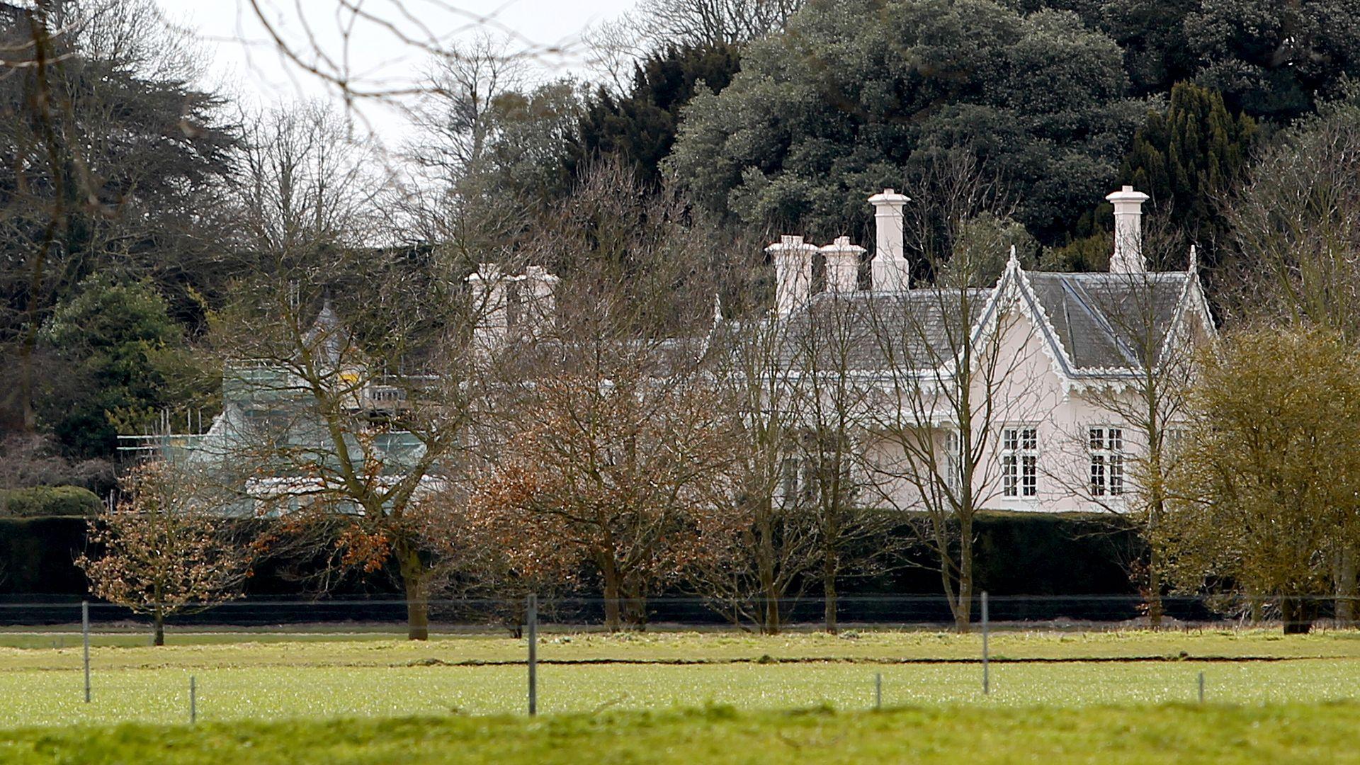 Adelaide Cottage is pictured against some small trees, it's a white house with pointy roofing eaves and chimneys with grass in front, taken in Windsor in 2013.