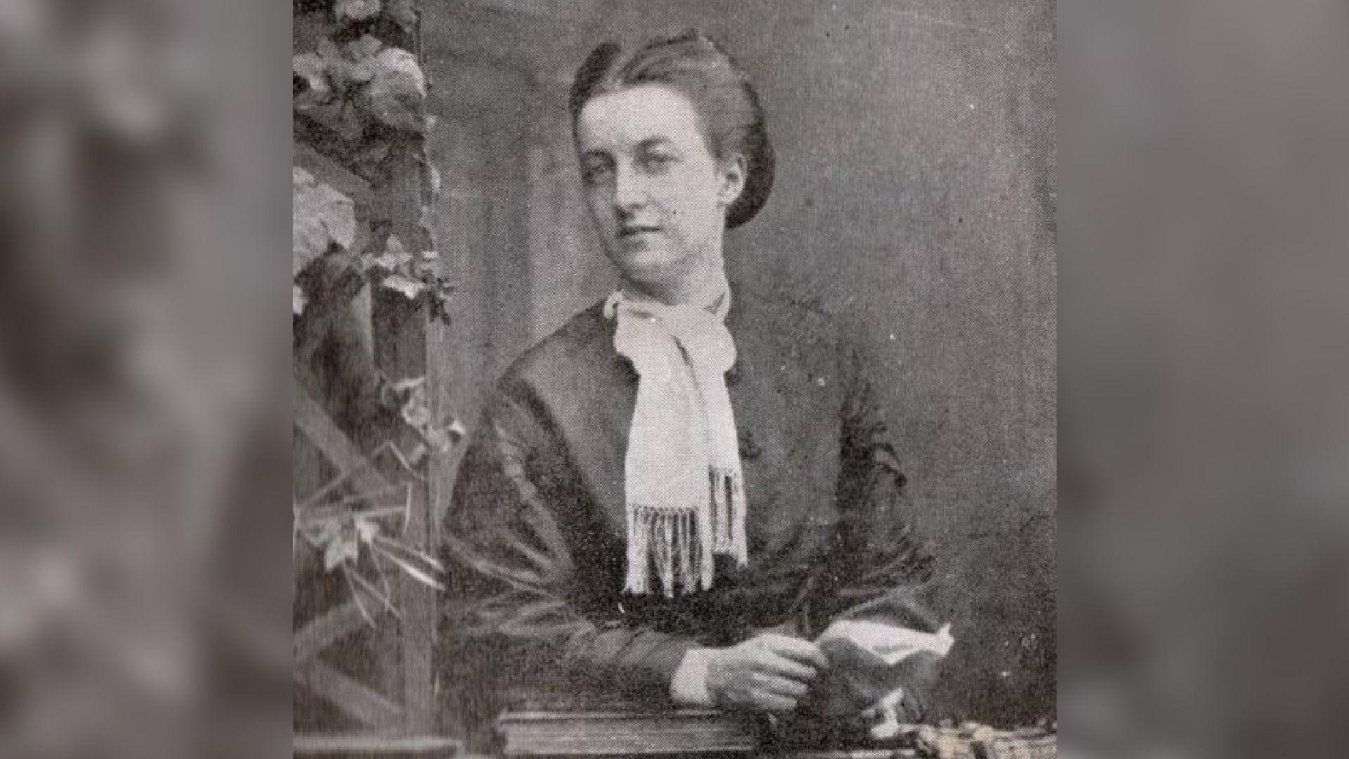 A black and white photo of Elise Sanders. She is wearing a dark coloured dress and white scarf