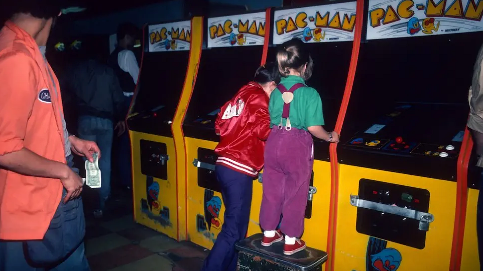 two kids playing pac man at an arcade